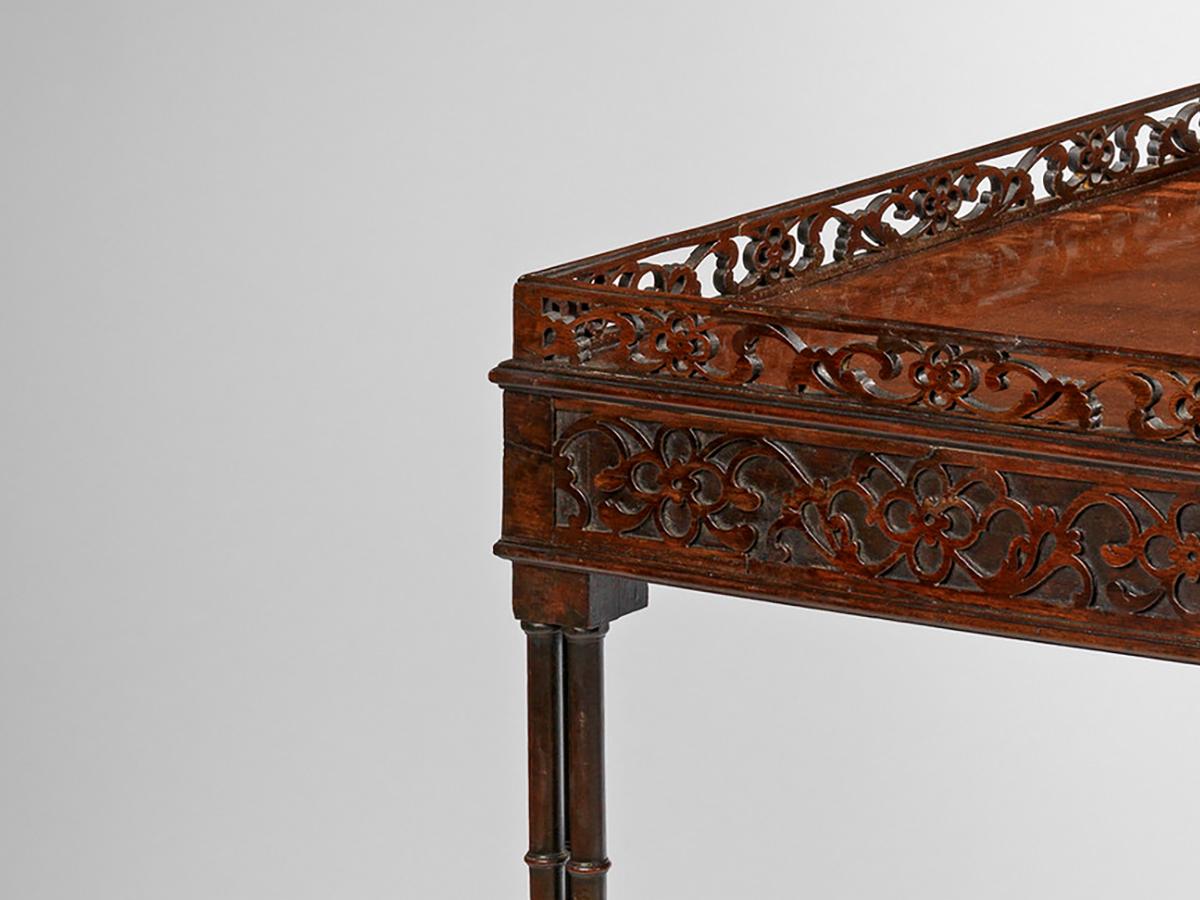 The rectangular top with an original pierced gallery above a blind fret-carved frieze, on circular cluster legs, terminating in block feet on leather castors? and joined by a rising pierced fretwork stretcher with central filial.

 