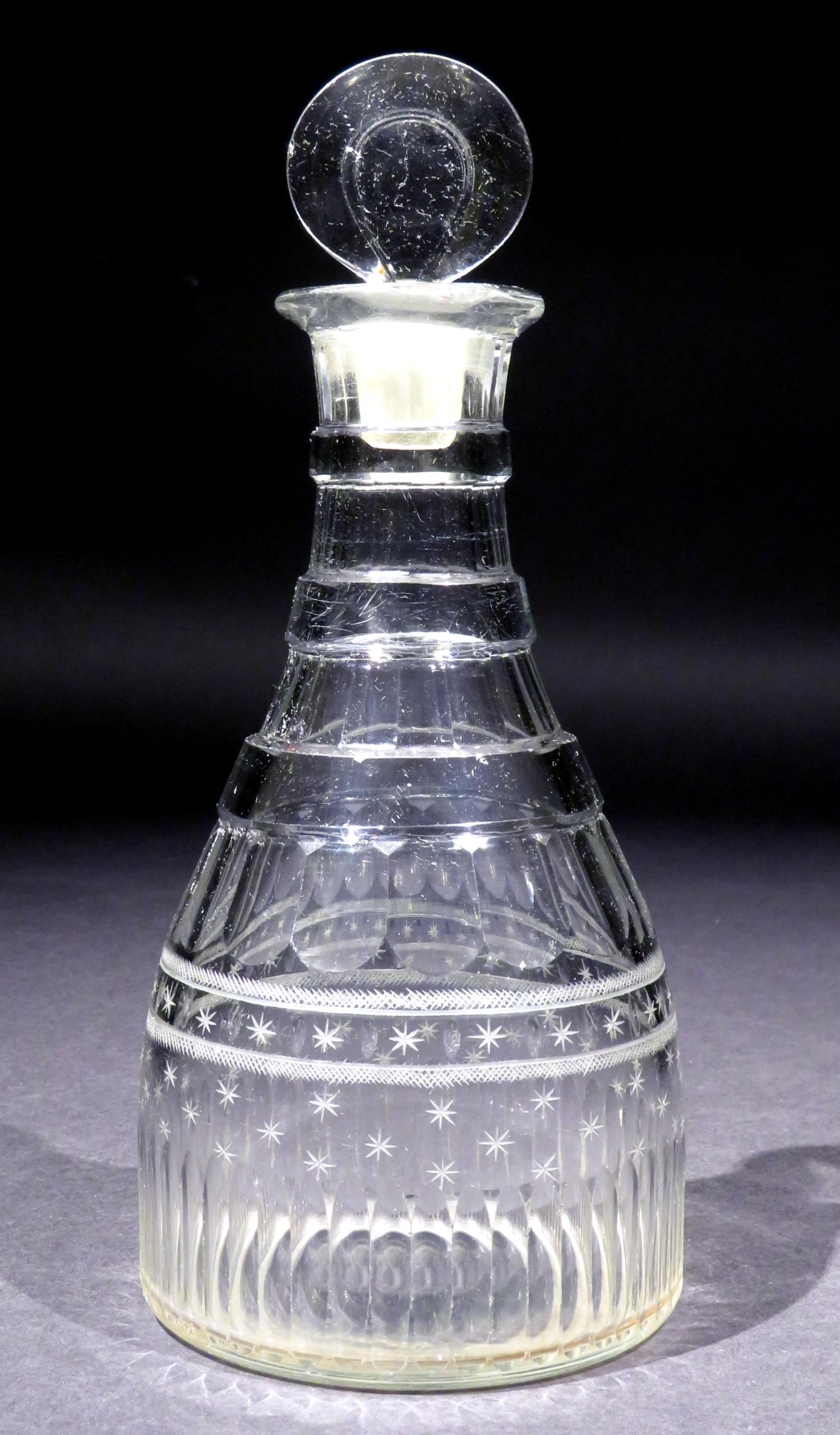 A very handsome Georgian Anglo Irish cut glass decanter, showing a base decorated with comb flutes & start cut motifs, rising to a neck decorated with three flat neck rings & basal flutes, ascending to it’s original target stopper.
The underside