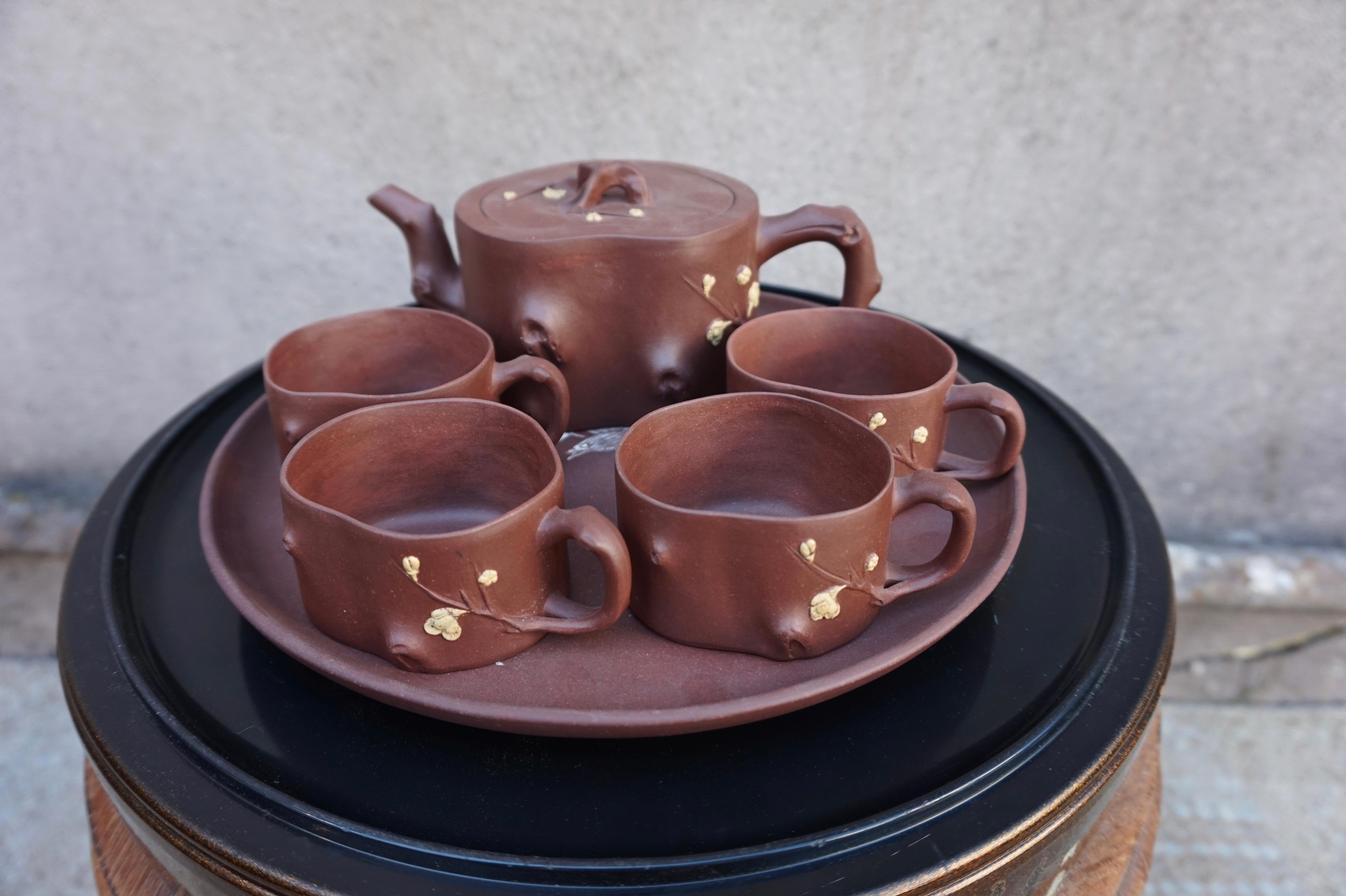 Daintily hand crafted Yixing wear tea set with beautiful shapes and blossom motif. The set comprises of four teacups and a single kettle and platter. The platter is not original to the set but comes with it. The kettle is stamped at the base. Yixing