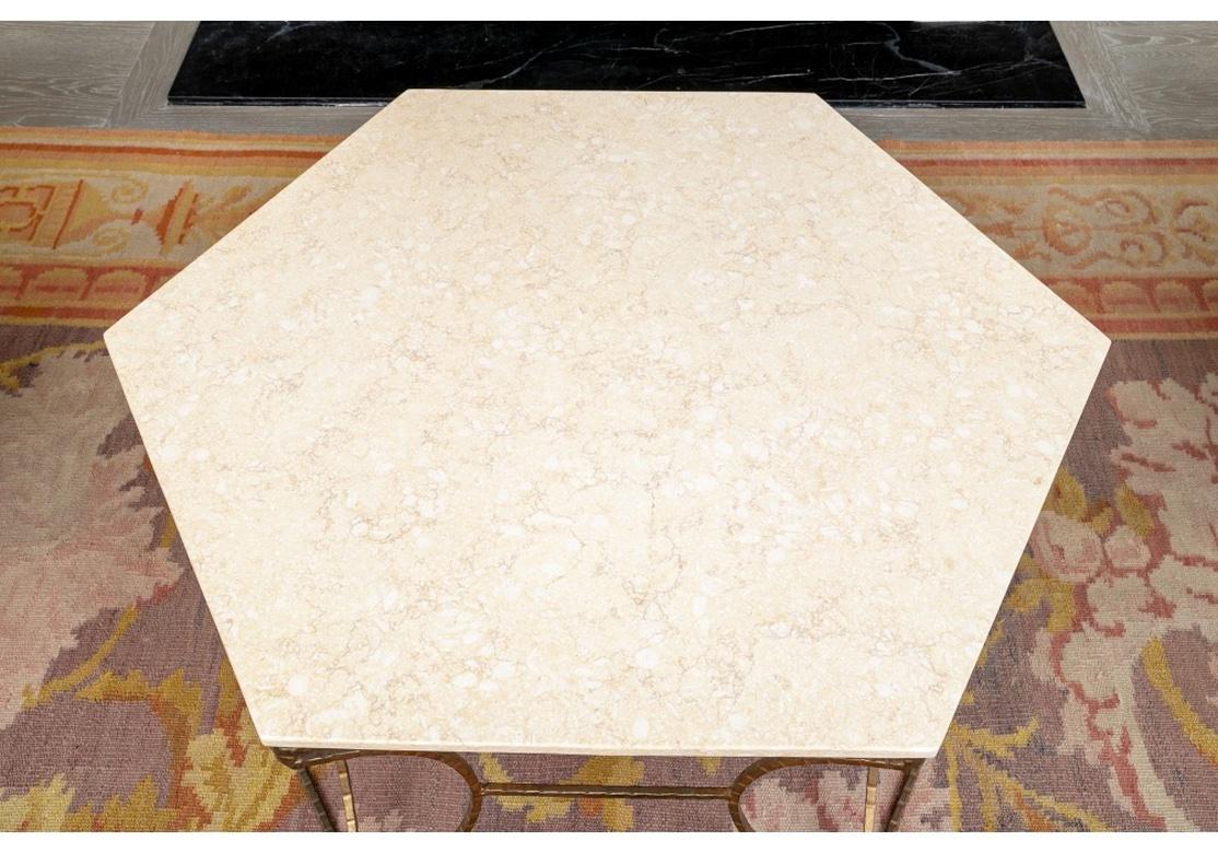 D'Interlude Home, une table à cocktail raffinée et délicatement fabriquée avec un plateau en pierre crème striée et polie soutenu par un cadre en faux bambou en fer doré. La table affiche une allure légère et aérienne tout en étant fabriquée à