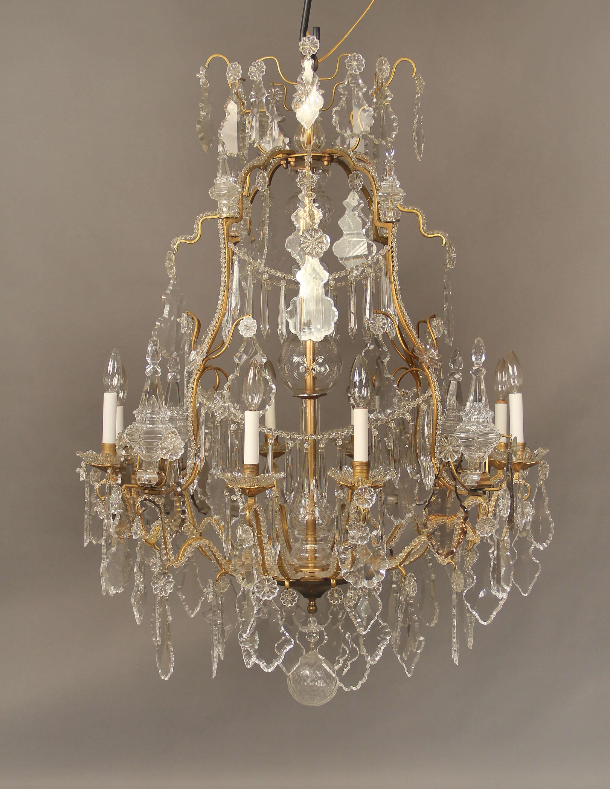 A very fine late 19th century gilt bronze and crystal eight light chandelier.

Multifaceted and shaped crystal, cut crystal central column, beaded frame and drop crystal swags. Eight-tiered spears and eight perimeter lights with bobeche