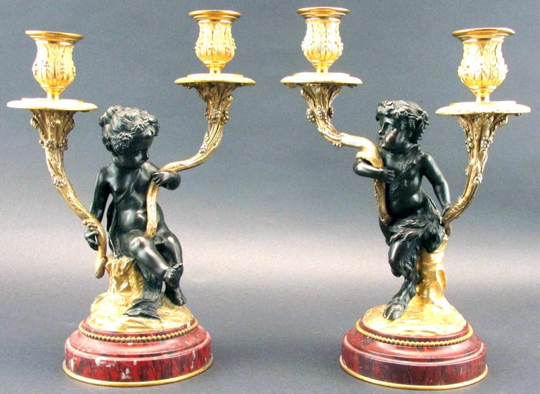 A very fine pair of 19th century parcel gilt bronze figural twin branch candelabra, executed in the manner of Claude Michel (Clodion) 1738-1814. Both depicting figures of a satyr & putto with finely sculpted & chiselled features, mounted atop