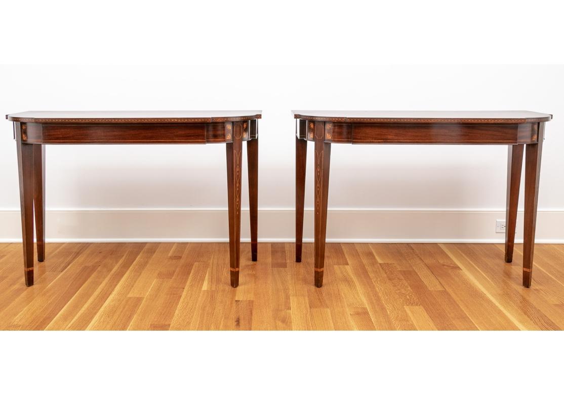 A particularly noteworthy pair of inlaid mahogany Demi Lune console tables with handsome wood having great graining and understated and lovely inlay work. Mahogany with shaped Demi lune  fronts and herringbone inlaid top edges. The frieze with