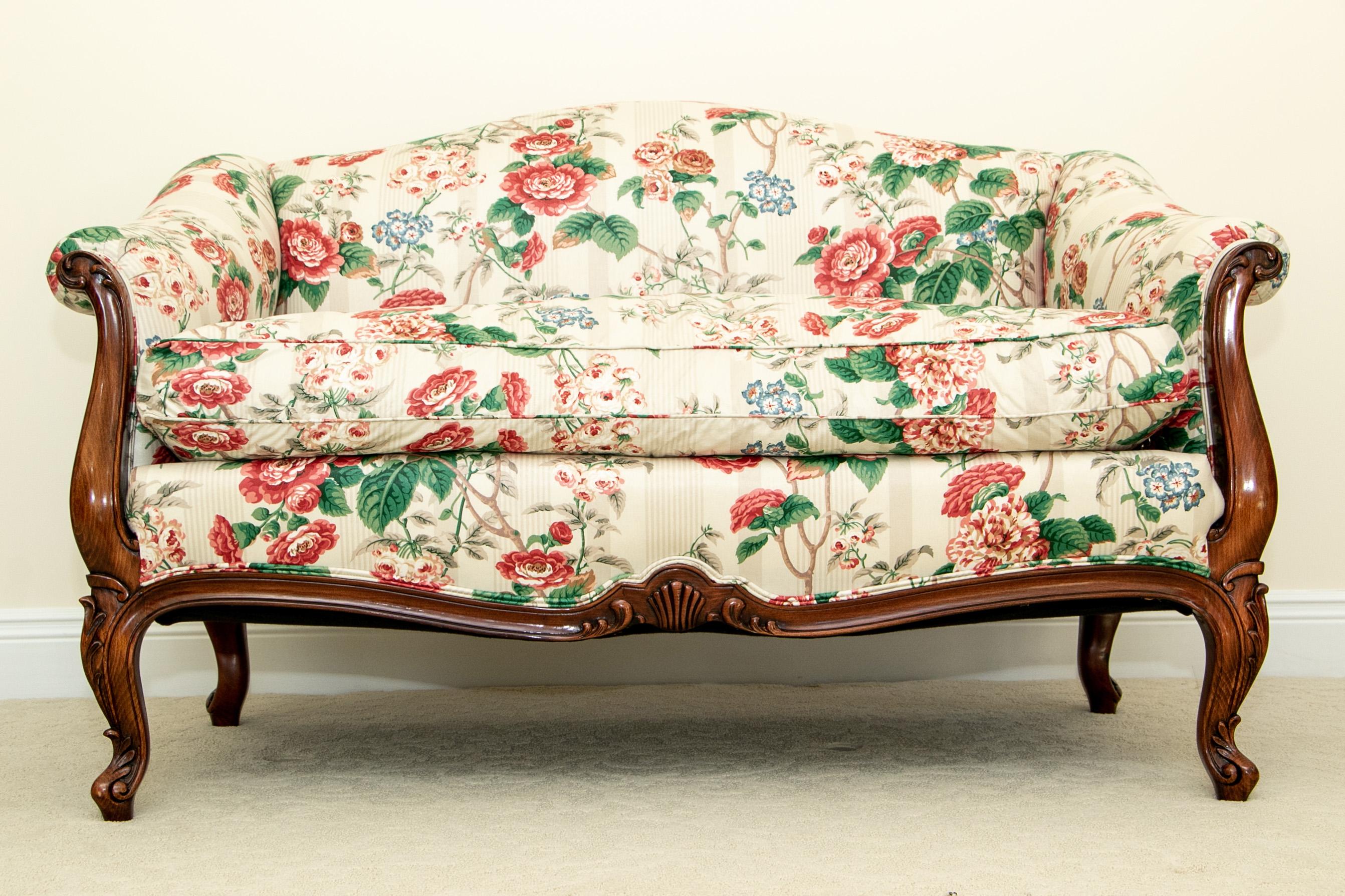 Louis XV style mahogany with shaped crest and carved leafy arms and cabriole legs. The lower front frame with a shell and leafy centre. Finely upholstered in a custom pink rose on gray stripe chintz fabric. Very comfortable seat cushions.