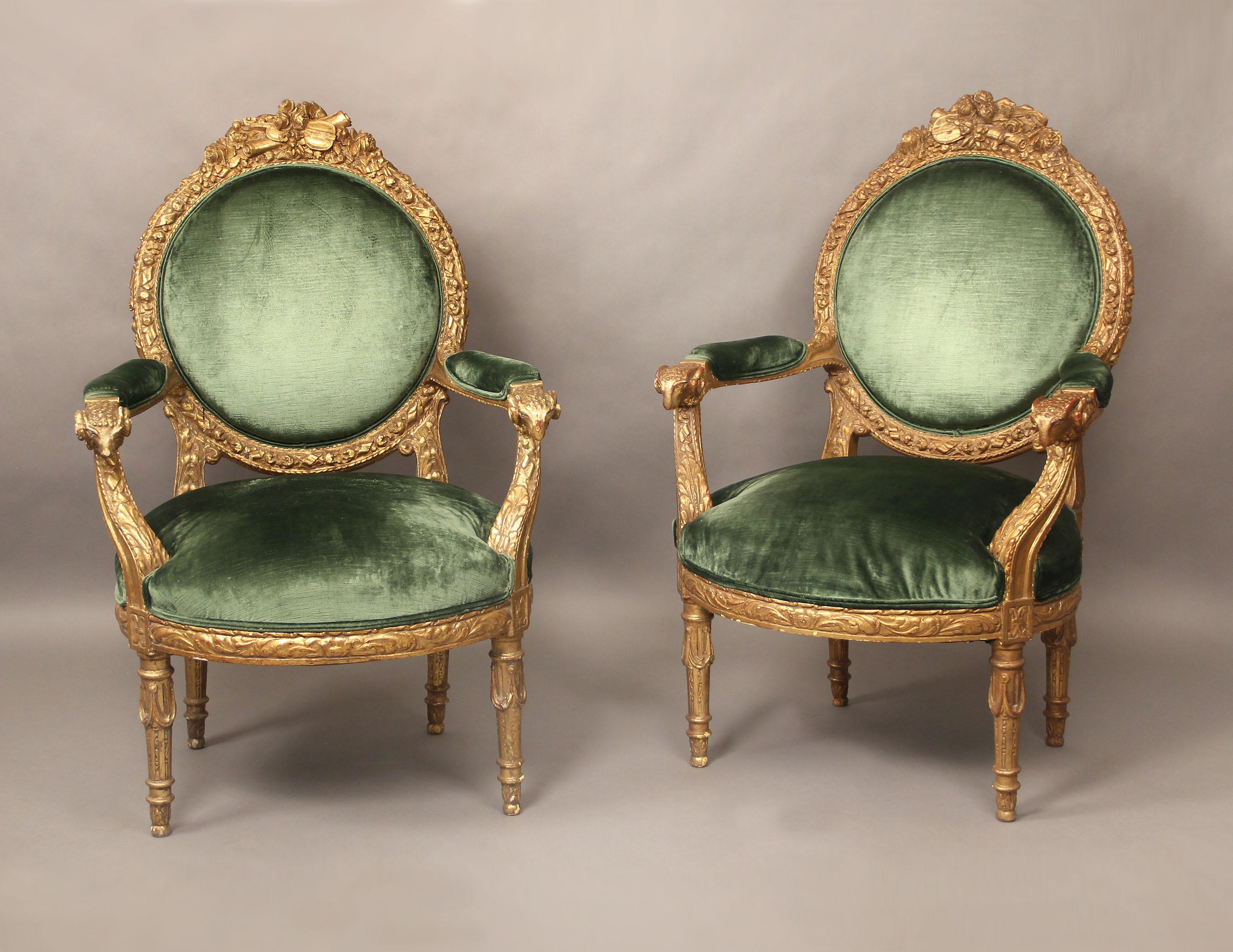 A very fine pair of late 19th century Louis XVI style giltwood armchairs.

Oversized with high backs, floral carved frames with instruments on top and ram's head on the arms.