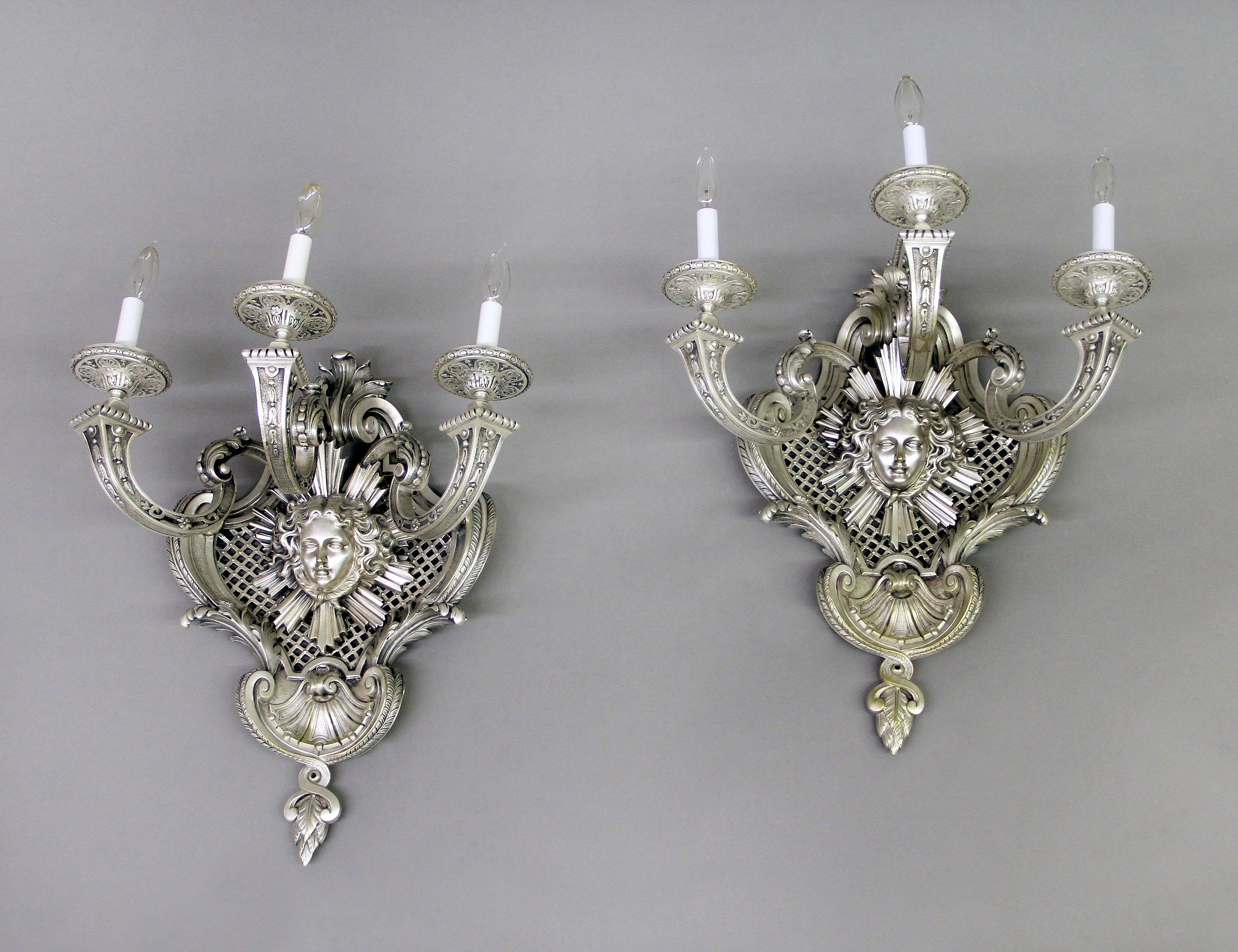 A very fine pair of late 19th century silvered bronze three light sconces

Centered with a mask of Apollo with rays of light, sitting on a reticulated base. Heavy chiseled detailed arms and cups, the top and base with foliage and shell