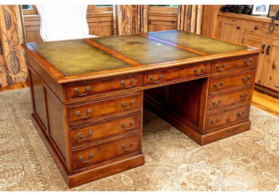 A large and very well made re-created Partners Desk with an authentic Antique English Style. In a honey tone wood with a three-sectioned green gilt-embossed leather top. With a center apron compartment that pulls out to hold a computer. Both sides