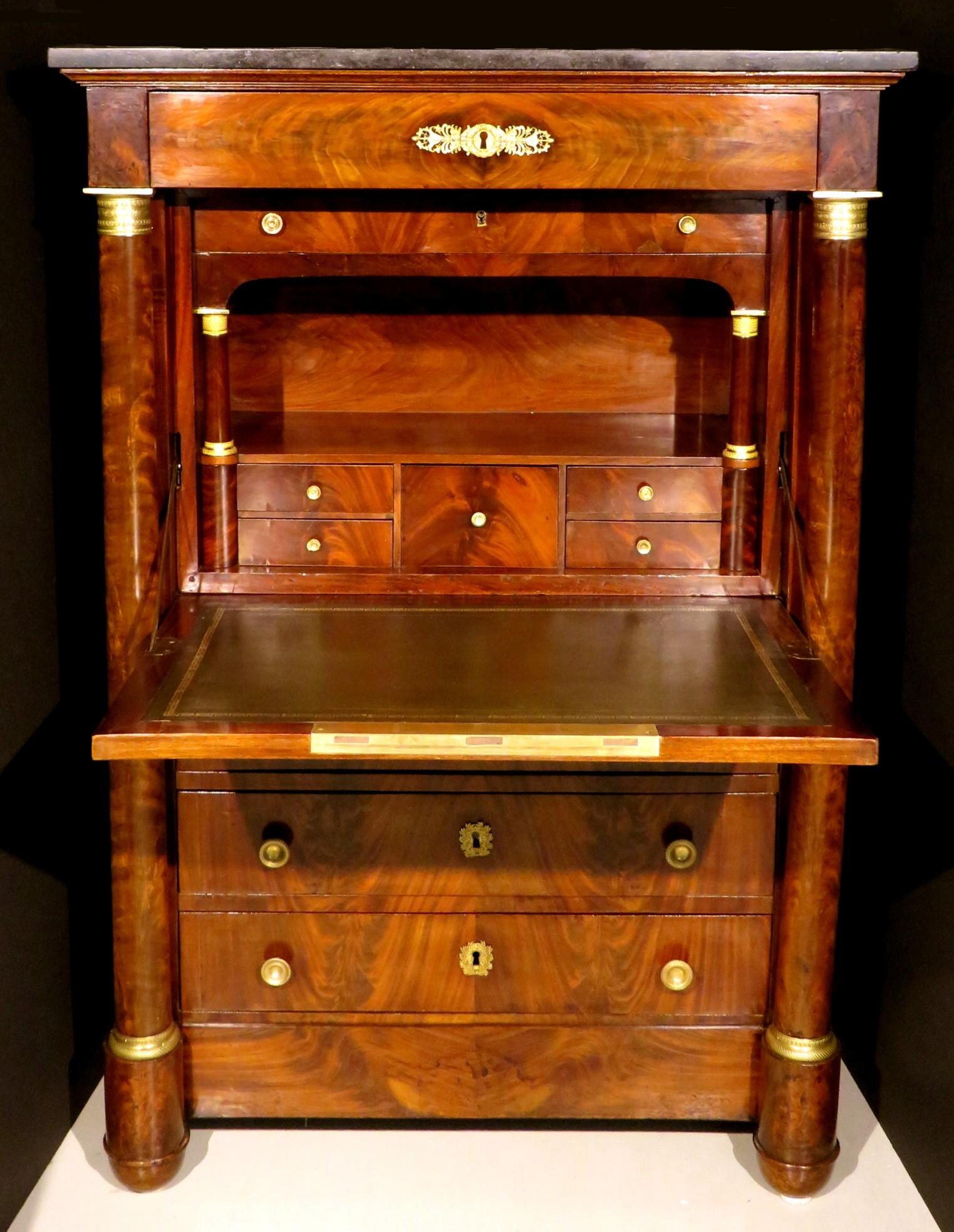 The richly figured mahogany case showing a black marble top over a single flush mounted drawer, the drop-down panel fronting an interior compartment housing small drawers and a gilt tooled leather writing surface, surmounting three tiers of