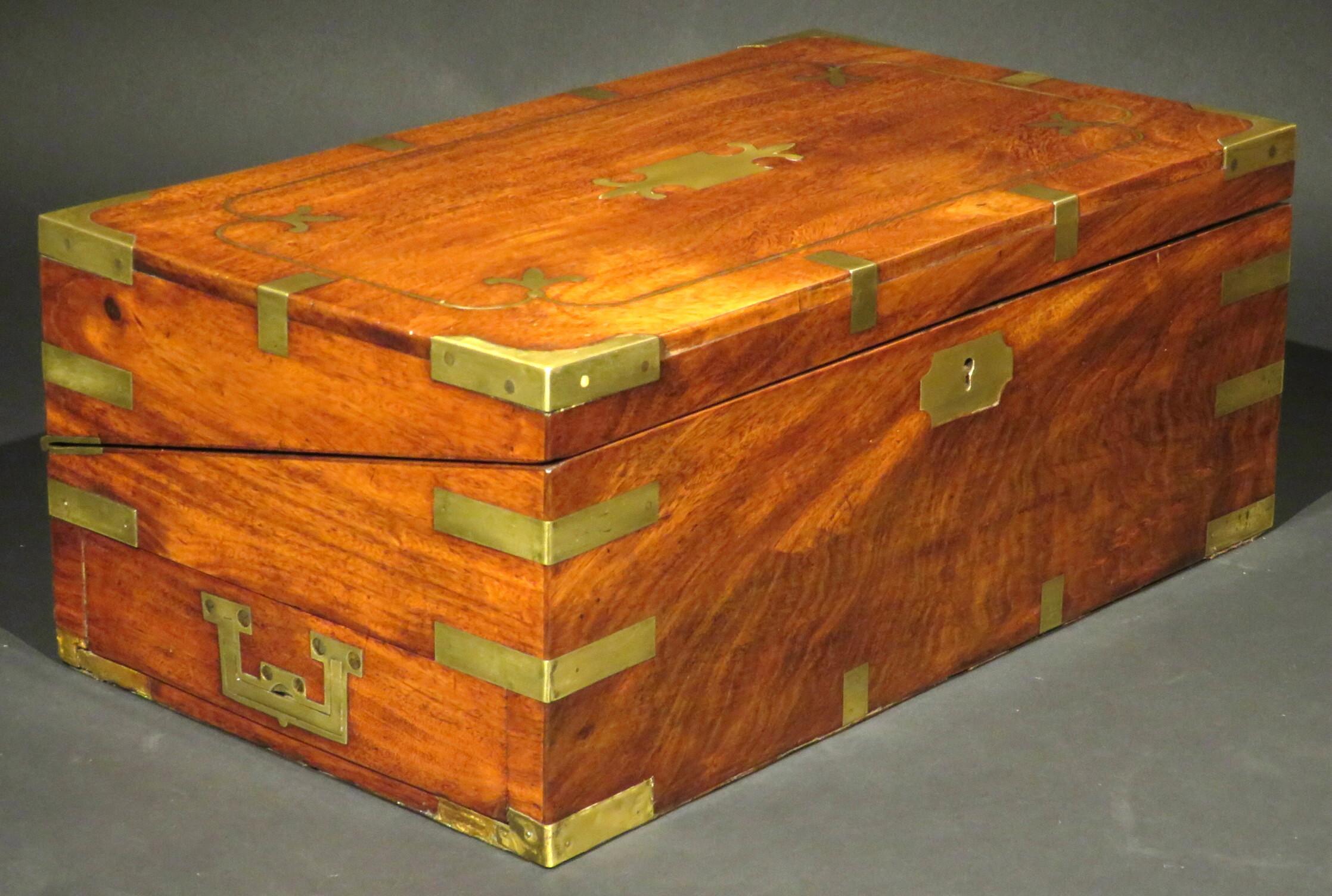 The finely grained and richly figured Honduran mahogany case bound with brass mounts and fitted with original flush mounted carrying handles – one affixed to a small drawer. The brass strung top opening to a fitted interior housing an inkwell and
