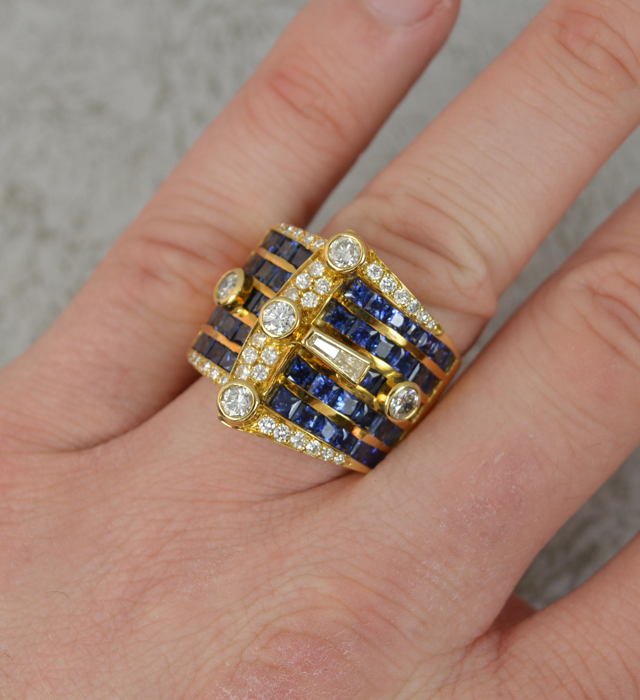 A stunning and over sized 18ct gold, sapphire and diamond ring.
Buckle shape design. Exceedingly heavy.
Set with many round brilliant cut diamonds, Vs clarity, 1.3cts total and five rows of princess cut blue sapphires.
22mm spread of stones, 22mm