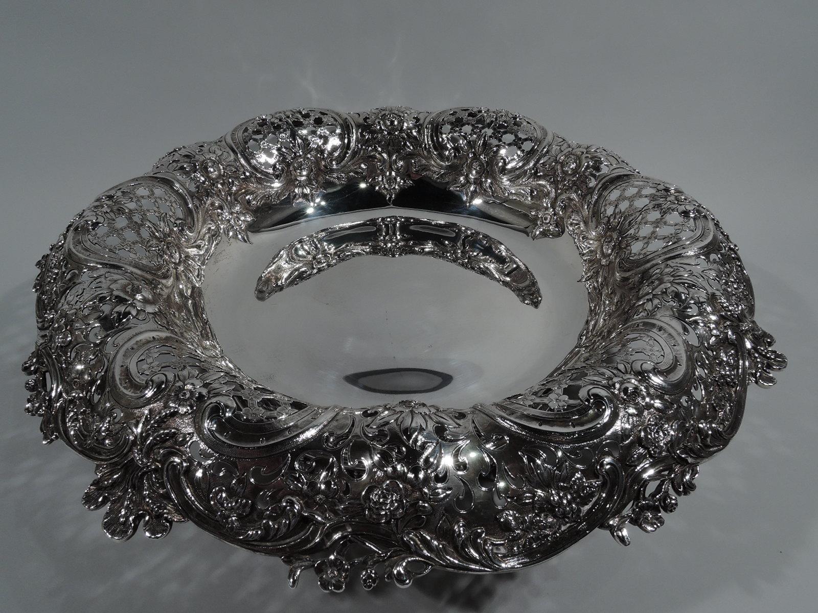 Wonderfully sumptuous sterling silver centerpiece bowl. Made by Tiffany & Co. in New York. Plain well with pierced and chased turned-down rim with flowers and trellis. Irregularly scrolled rim interspersed with leaves and flowers. Foot ring has 6