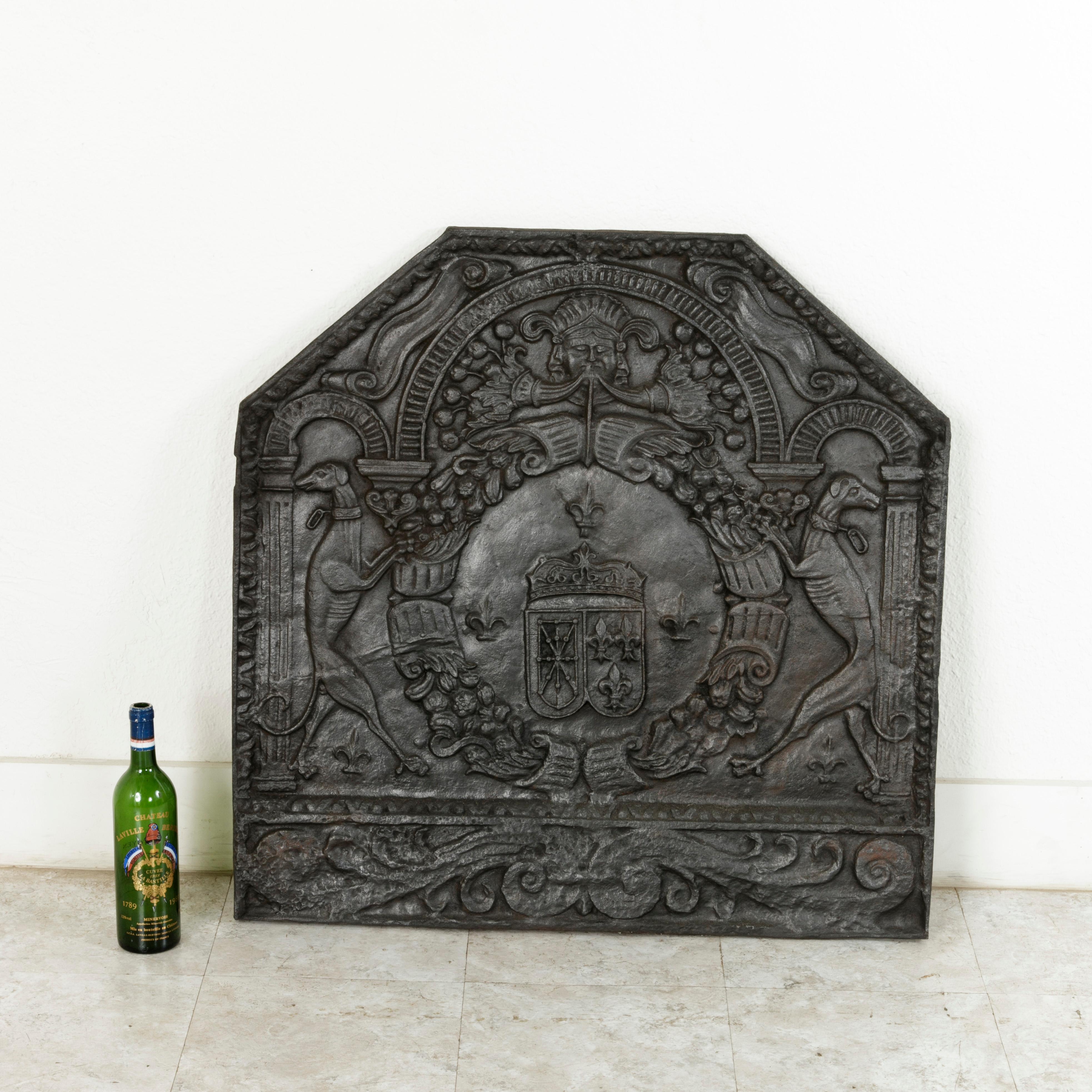 Measuring nearly 34 inches square, this very large mid-18th century French Louis XV period iron fireplace back features a heraldic motif with the coats of arms of France and Navarre side by side in the centre with a crown above. A symbol of the