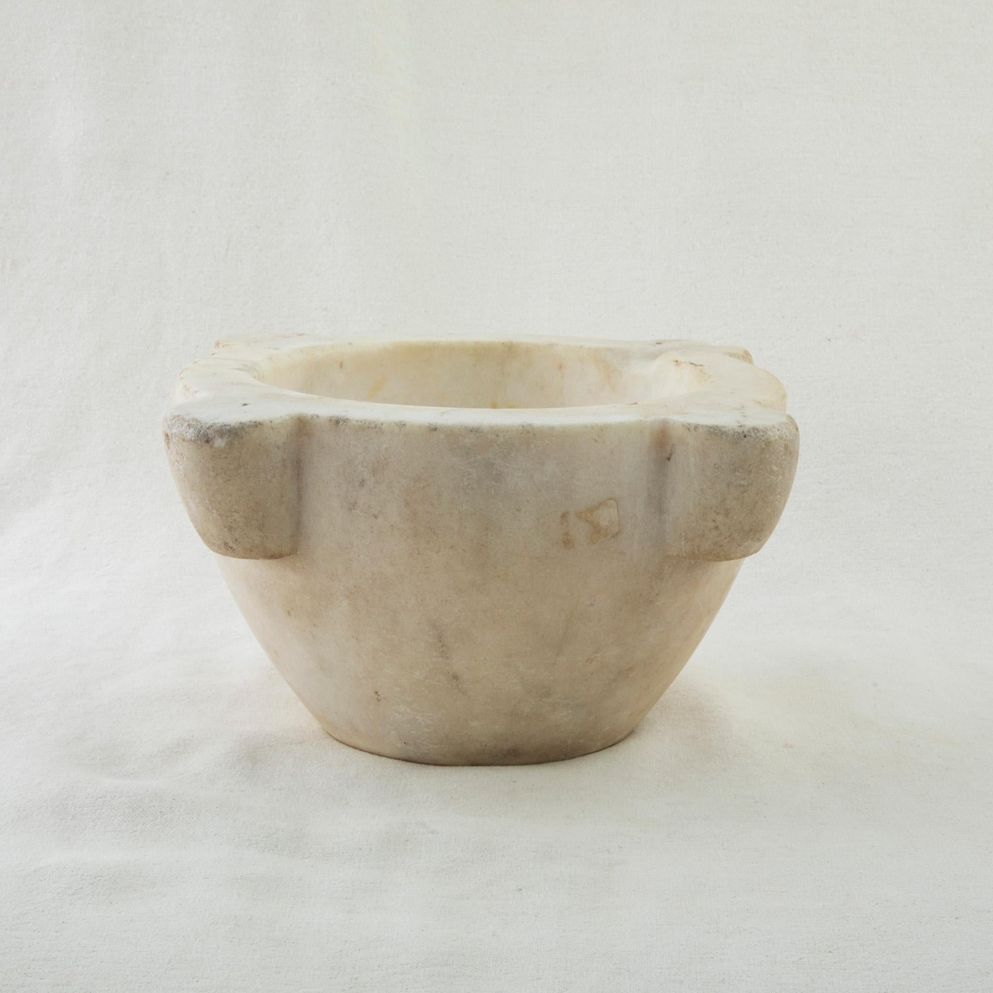 This large marble mortar from the nineteenth century is made from a single block of Carrara marble and features its original turned pestle made of alder wood. Once used by a pharmacist to grind herbs for medicinal purposes, it can now serve as a
