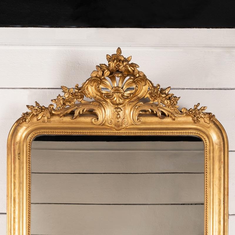 Très grand miroir en bois doré gravé de motifs floraux. Très belle dorure d'origine, miroir au mercure, plancher en bois.
France, 19ème siècle.

Hauteur 180 cm - 70,87 po
Largeur 103 cm - 40,55 po