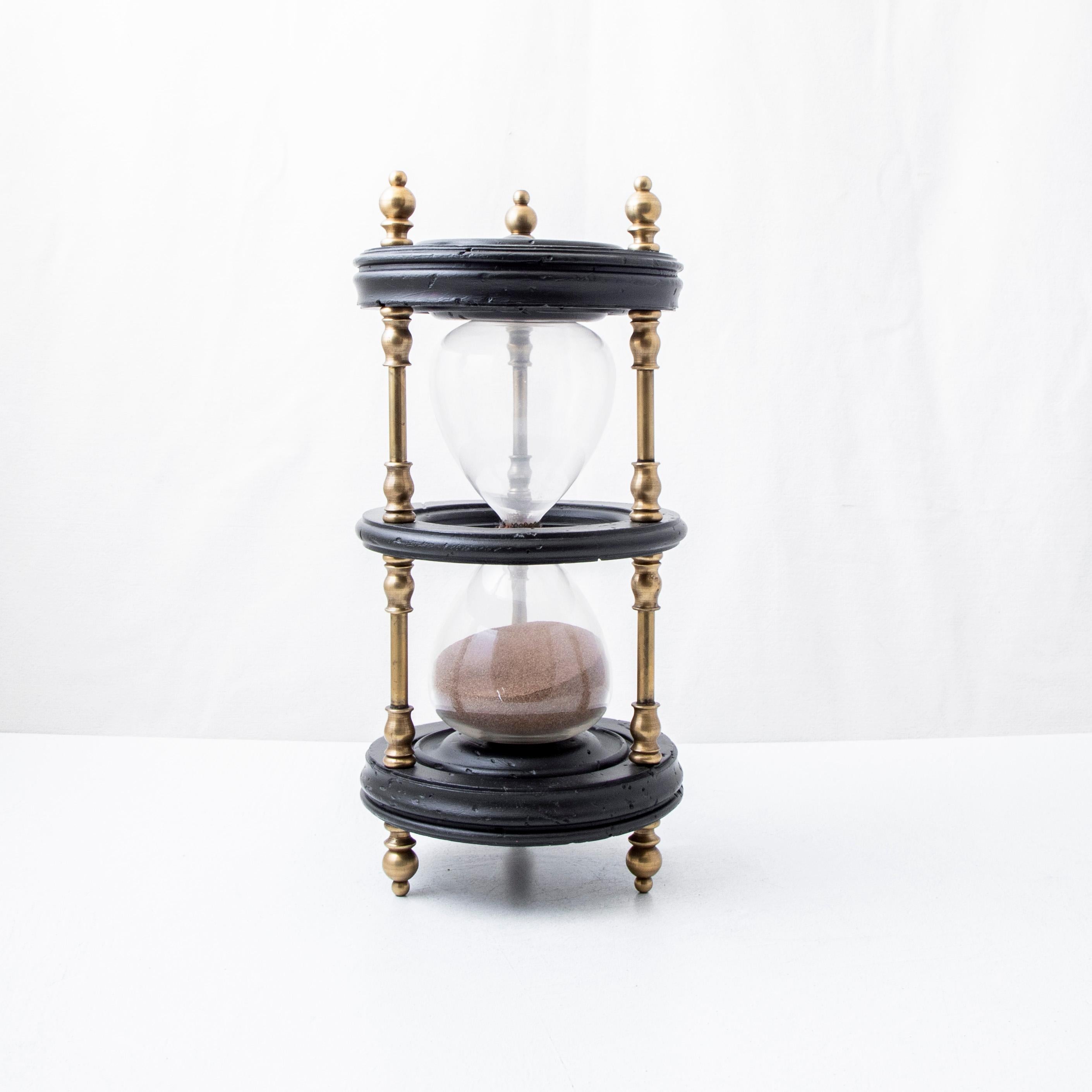 Standing at 16 inches in height, this large scale nineteenth century Napoleon III period hourglass features three turned ebonized wood disks joined by bronze supports and finished with bronze finials. Originally used aboard a ship while at sea, the