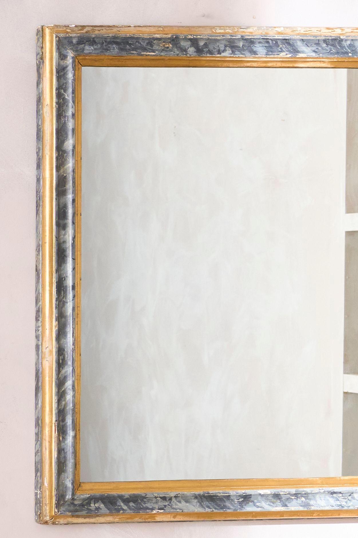 Il s'agit d'un superbe miroir mural du début du 19e siècle, décoré au gesso et à la dorure. Le cadre est entièrement d'origine et présente une décoration peinte en faux marbre dans une couleur gris-bleu très subtile avec des détails dorés. L'état