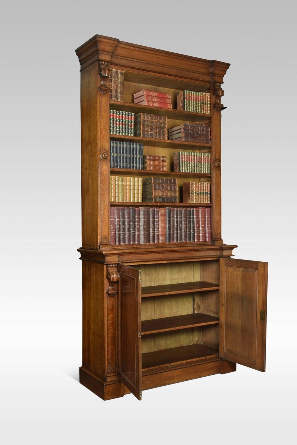 19th century oak bookcase with a flared cornice over a large open top bookcase with four adjustable shelves, the base section fitted with two panelled doors enclosing shelved interior. All raised up on plinth base
Dimensions:
Height 103.5