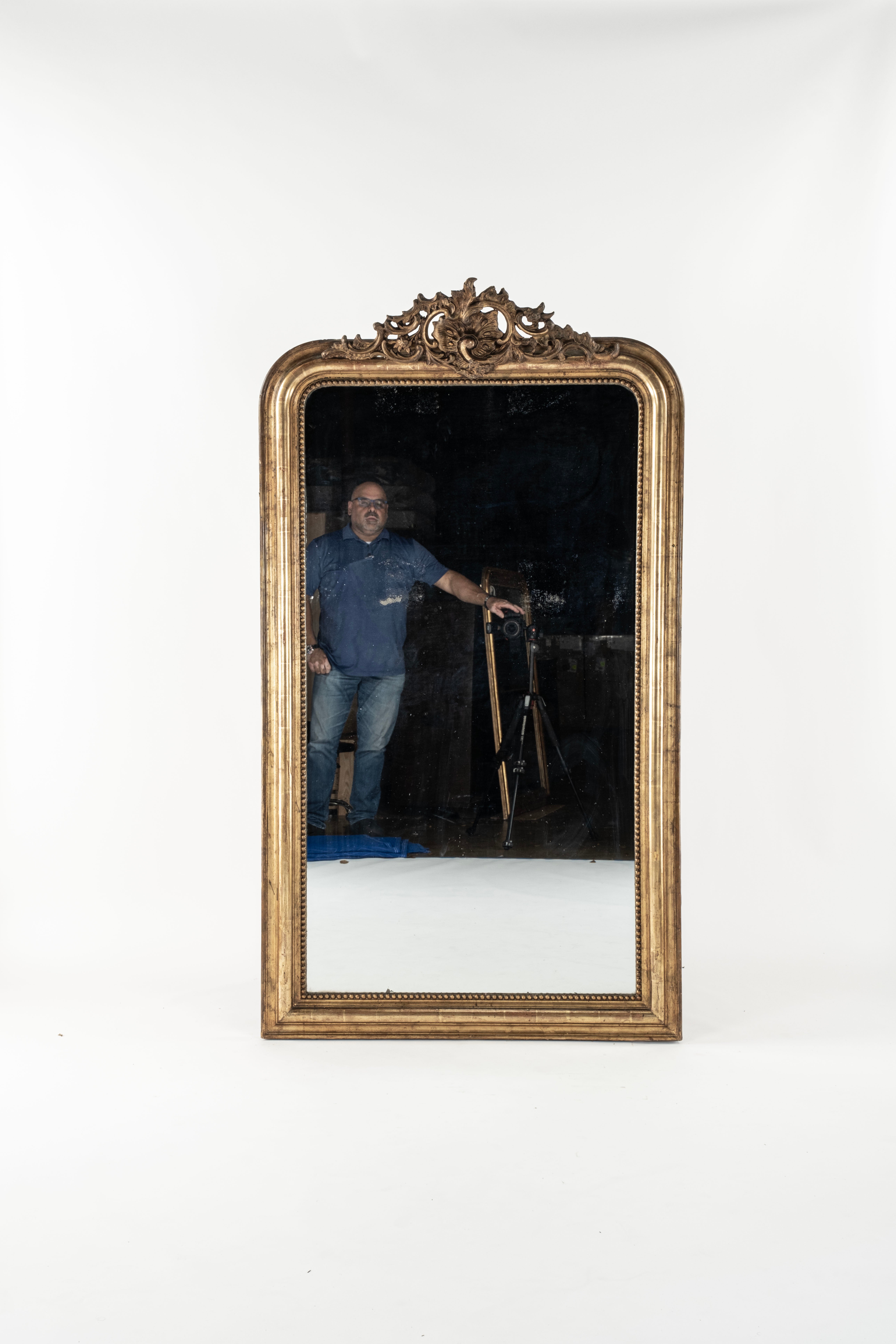 Miroir français ancien - Grand miroir ancien Louis Philippe d'époque, à crête dorée. Finition en deux tons dorés sur rouge d'origine. Verre de mercure ancien avec quelques petites zones patinées. Dos à panneaux anciens. Vers 1840.  Taille :  72 