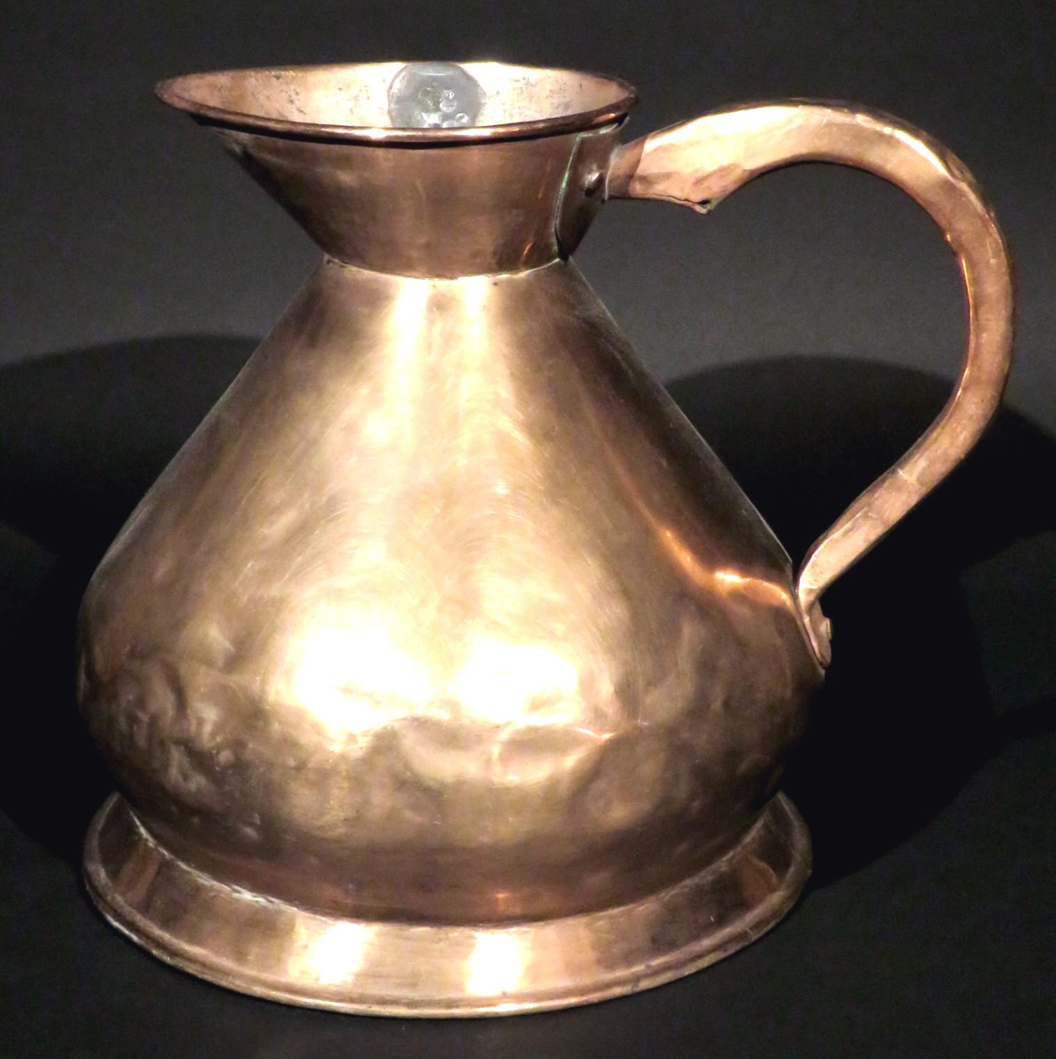 A very large two gallon copper haystack-shaped measure / ale pitcher of dovetailed construction, rising to a flaring and elongated spout inset with its lead seal noting volume, maker etc. The body fitted with a riveted handle and raised overall upon