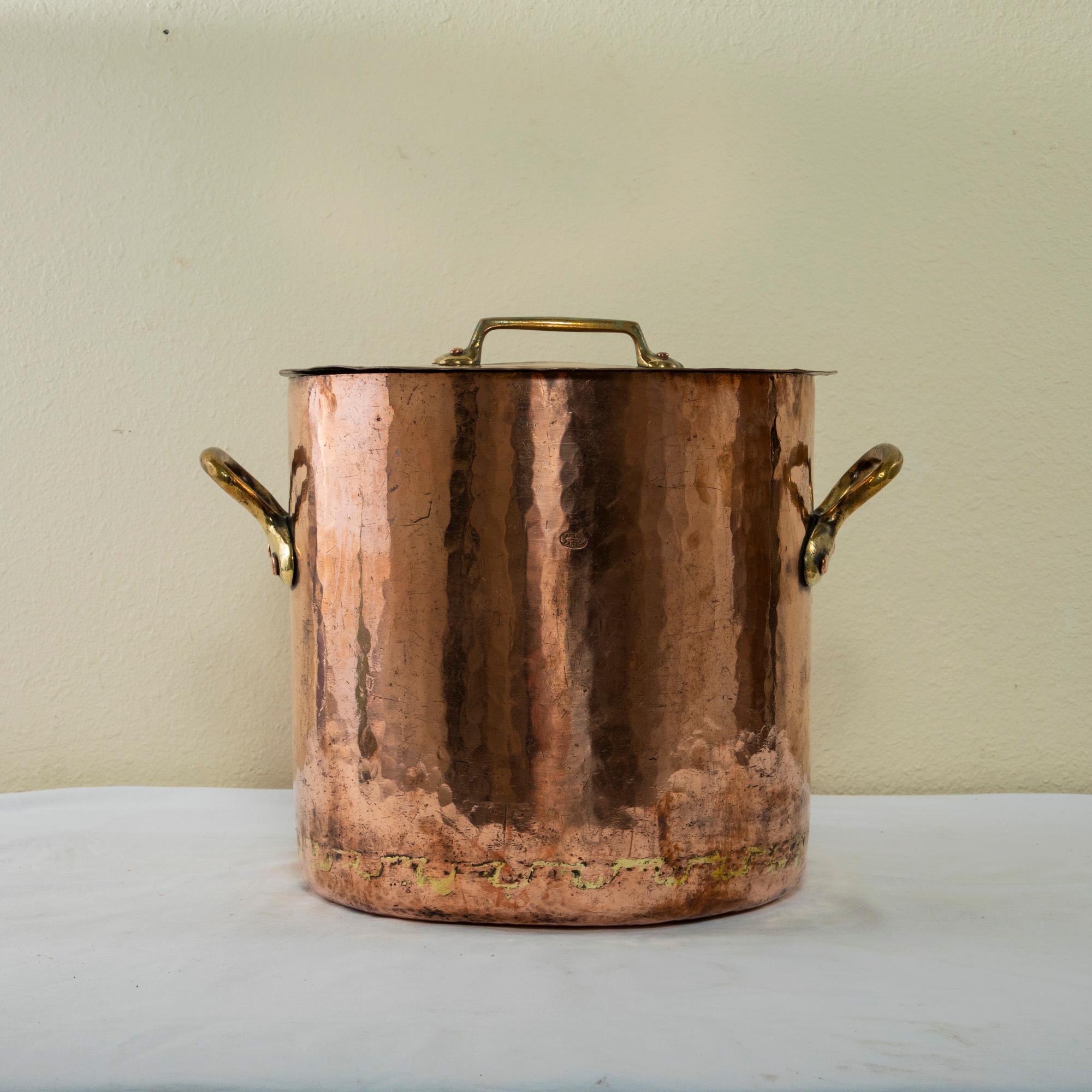 Originally used to make jams, this large French mid-twentieth century copper stock pot is hand hammered and features its original lid with copper riveted brass handle. Brass handles are additionally fitted to the sides of the pot to allow for easier