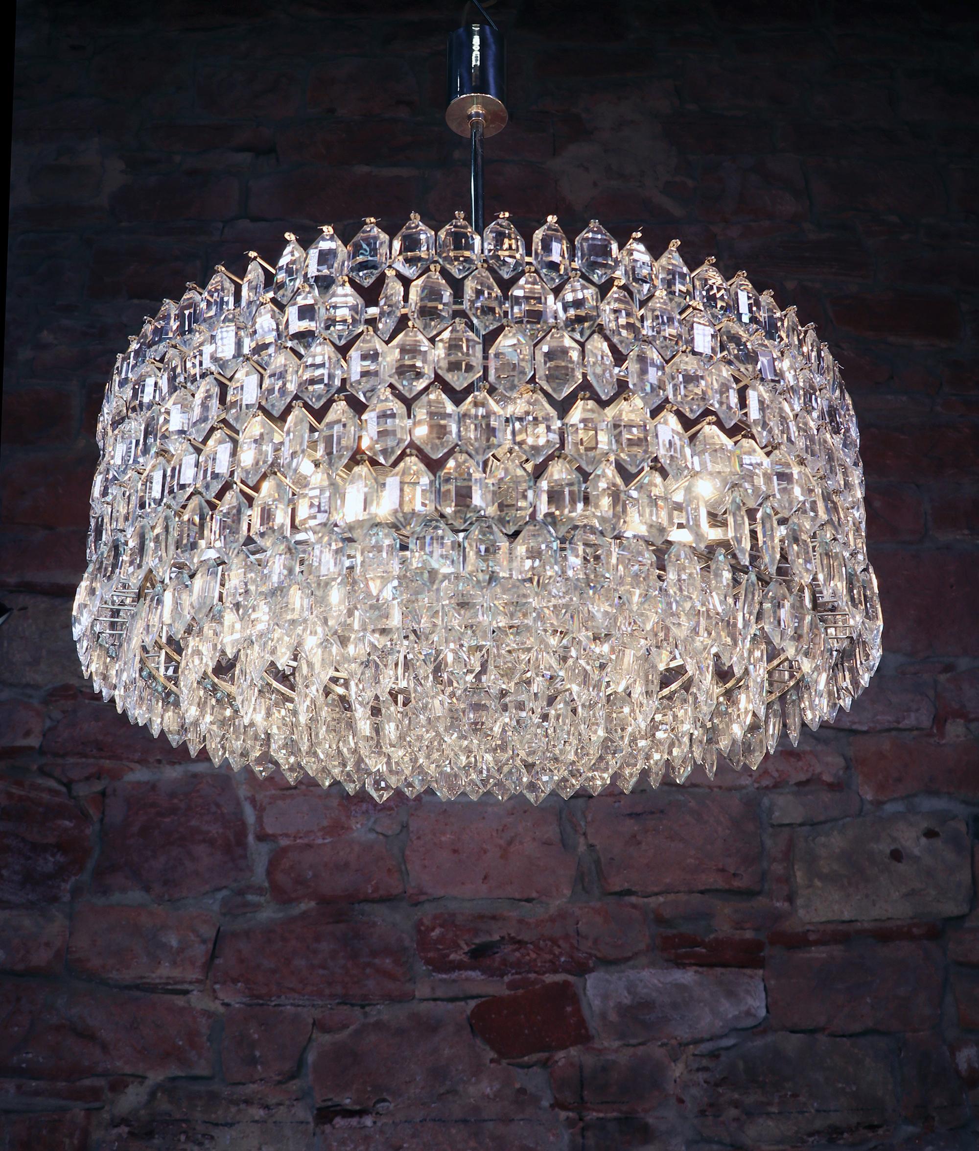 Stunning huge cluster with numerous faceted crystals arranged in six rows on a silver plated frame. Chandelier illuminates beautifully and offers a lot of light. Gem from the time. With this light you make a clear statement in your interior design.