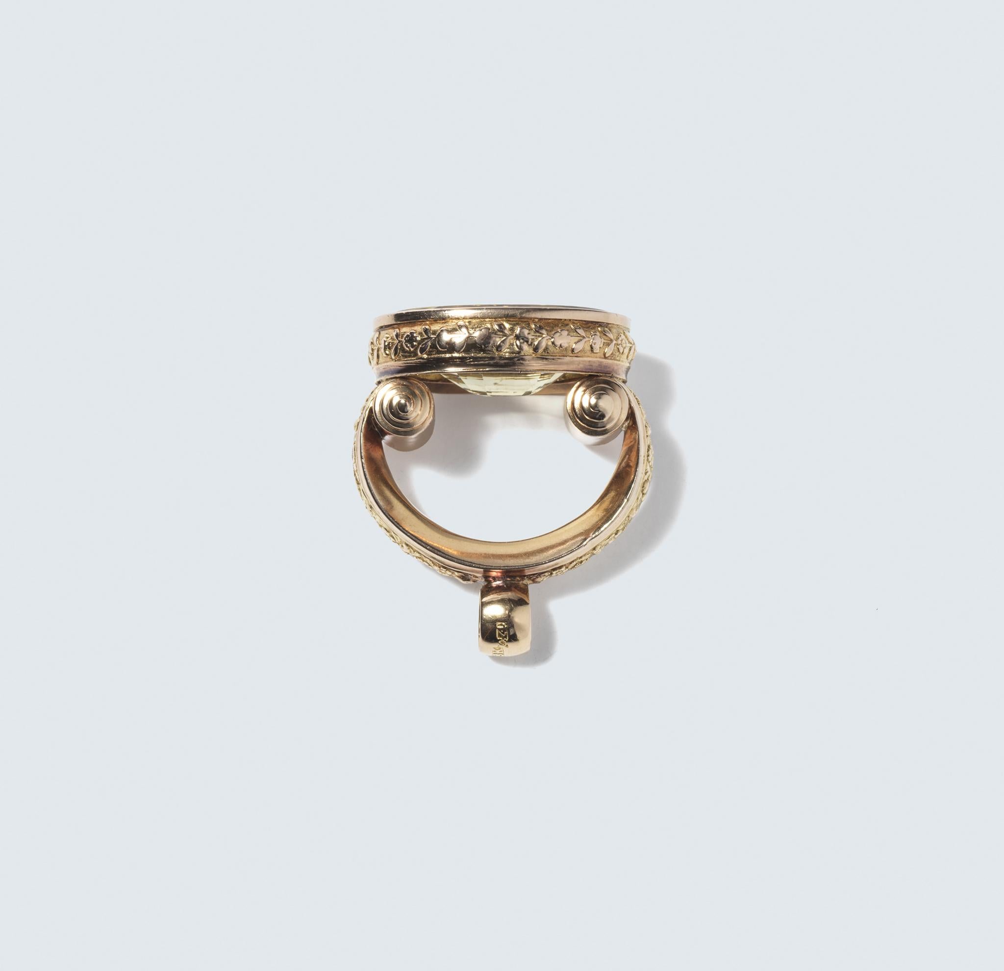 This ring boasts an 18 karat gold setting with a large, oval-shaped citrine stone as its centerpiece. The citrine is faceted, giving it a multi-dimensional surface that catches and reflects light. The gold that encases the citrine is textured,
