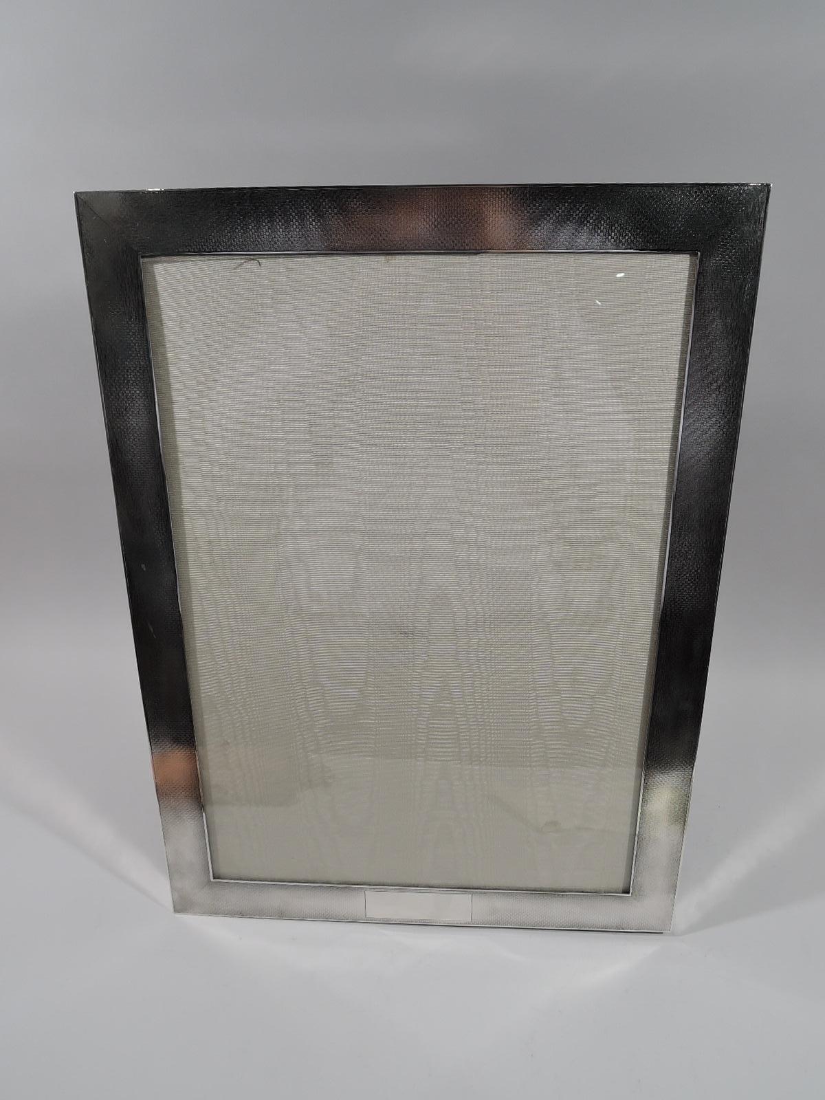 Very large sterling silver picture frame. Made by William B. Kerr in Newark, circa 1910. Rectangular window in flat surround with all-over engine-turned basket weave; sides plain. Rectangular cartouche (vacant). With glass, silk lining, and velvet