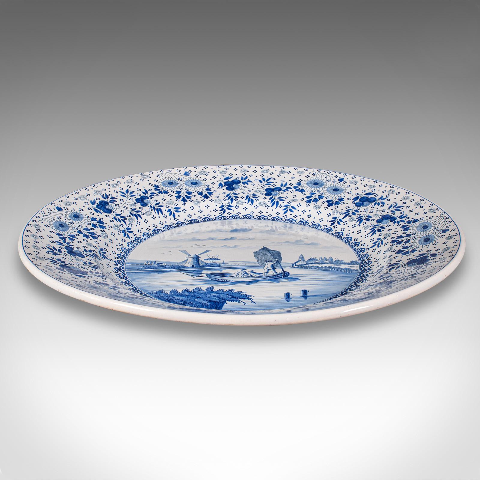 This is a very large antique decorative serving plate. A Belgian, ceramic charger with blue and white finish, dating to the early 20th century, circa 1920.

Of Impressive size, with a delightful blue & white appearance
Displays a desirable aged