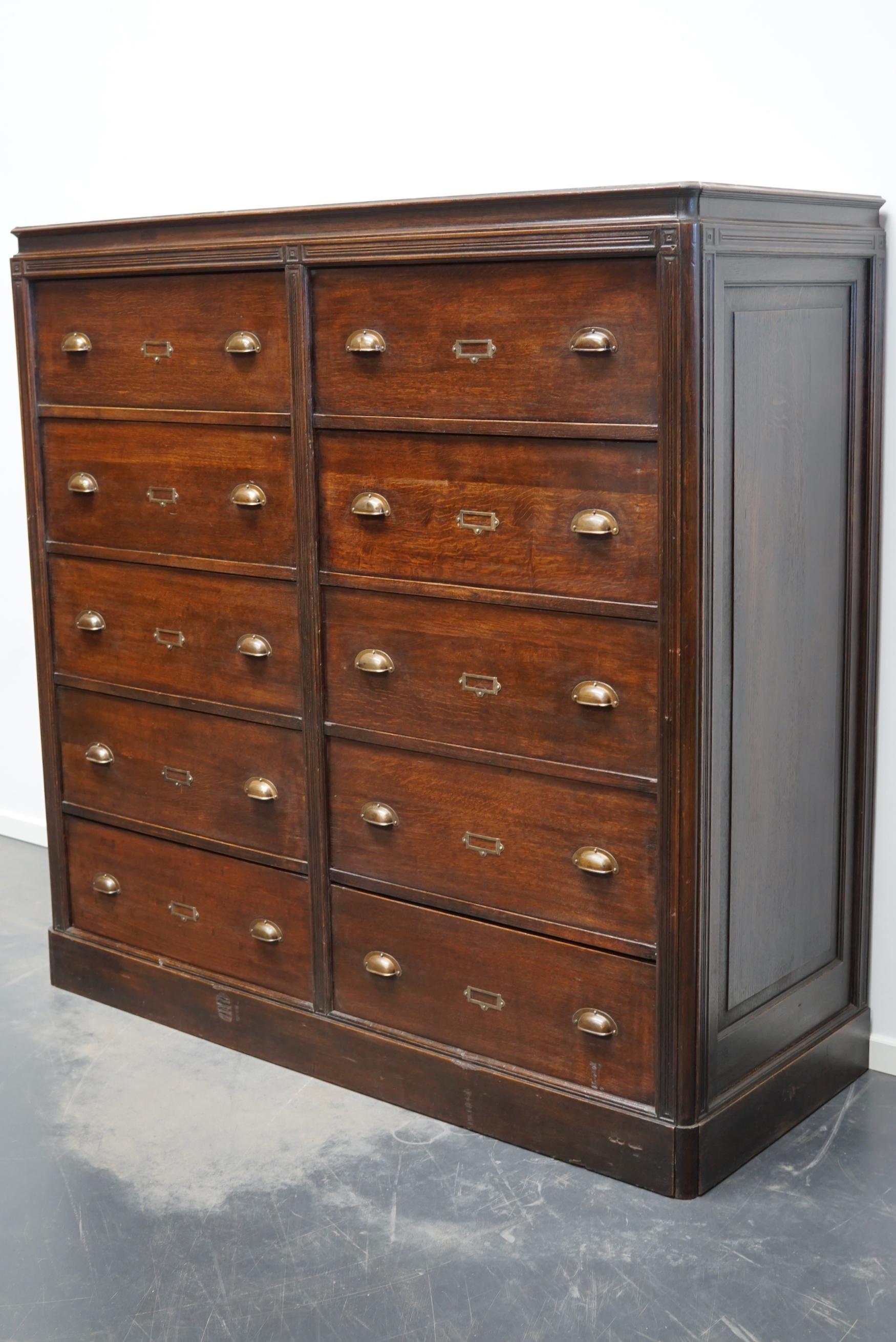 This oak apothecary cabinet with brass hardware was made in the early 20th century in France and was used to store sewing patterns. It is very well made and it remains in a good condition. The large drawers make it a very functional cabinet. The