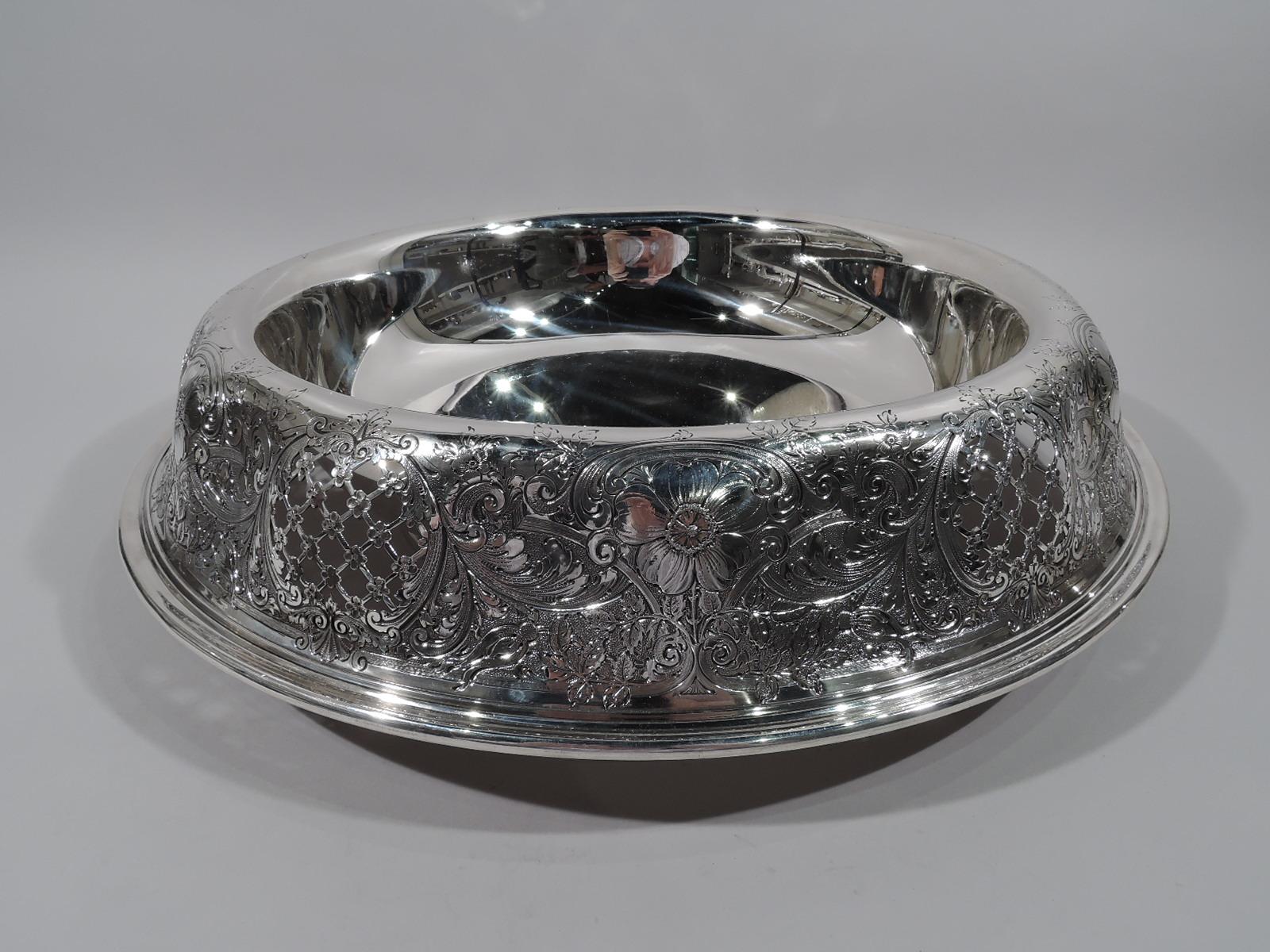 Very large Edwardian sterling silver bowl. Made by Gorham in Providence in 1912. Plain well with lobed and turned-down sides with fluid and dynamic chased and engraved ornament comprising pierced floral diaper set in scrolled frames alternating with