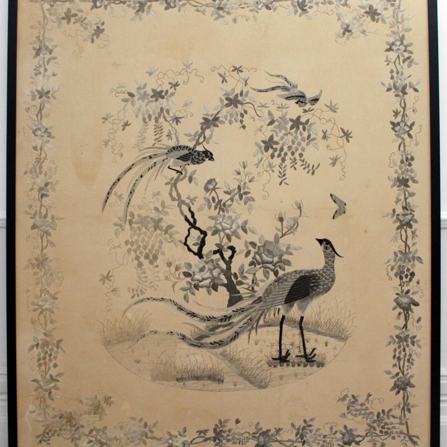 This extremely large piece of Chinese embroidery is stitched in silk. The subject is two birds in a traditional setting of a leafy tree with butterflies fluttering about in the distance. Apart from the scale, what really sets this piece apart is the