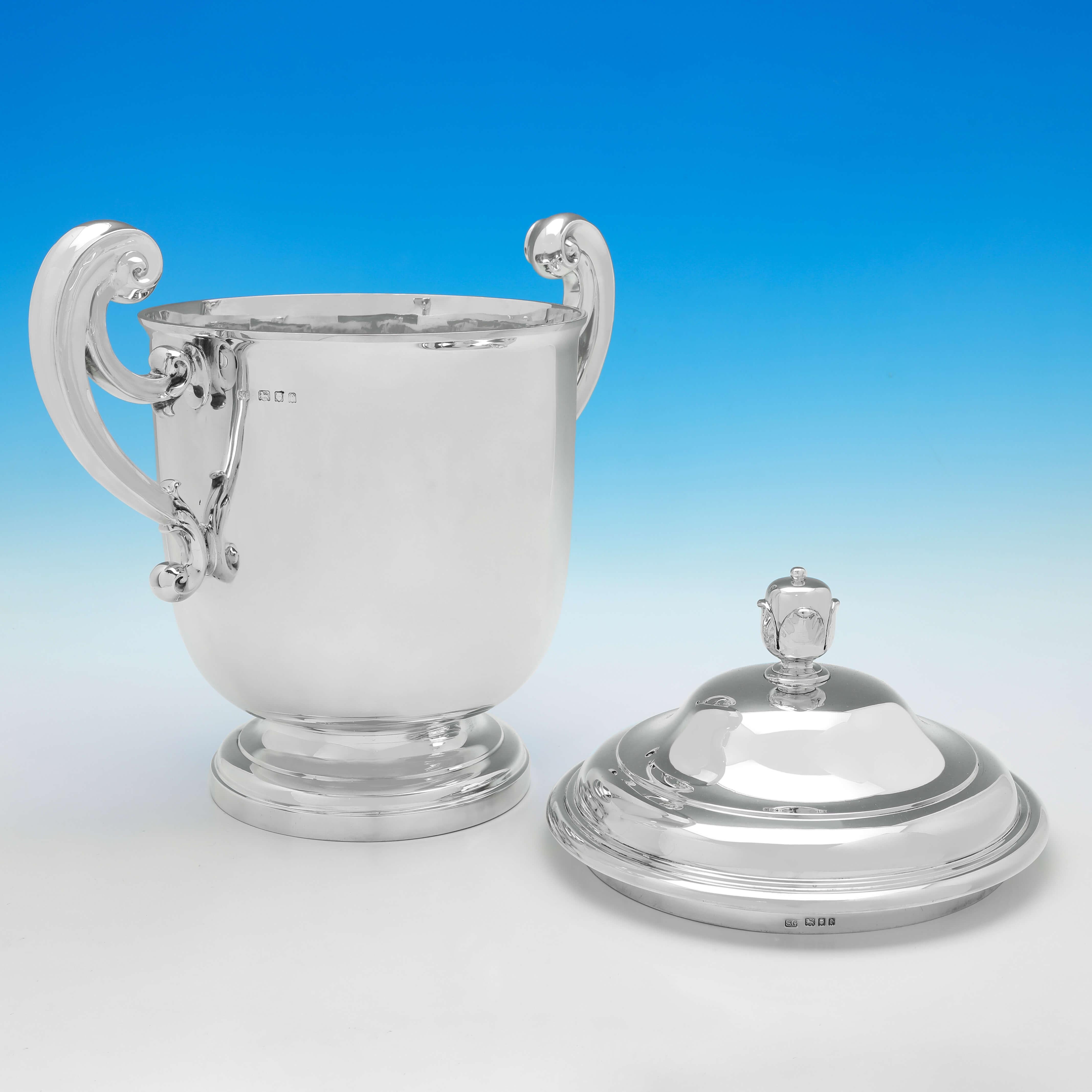 Hallmarked in London in 1920 by Garrard & Co., this very large and very handsome, Antique Sterling Silver Trophy, is of traditional form, with scroll handles, and a removable lid. 

The trophy measures 17.25