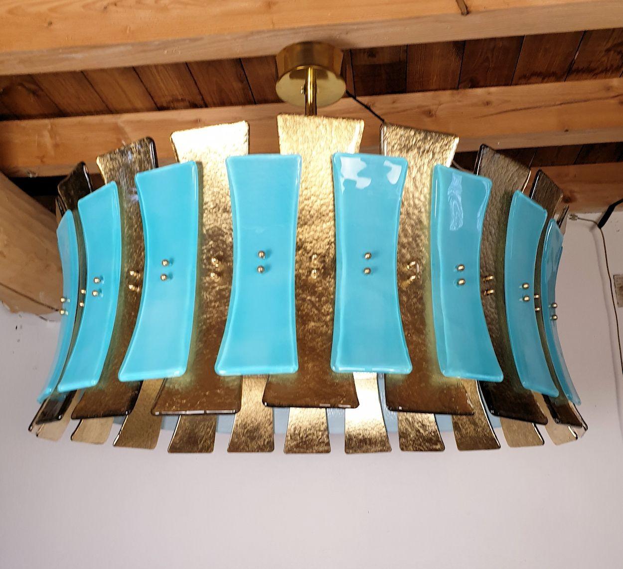 Large Blue & Gold Leaf Murano glass Drum chandelier, Mid Century Modern style, Italy circa 1990s
The large Italian chandelier is made of two layers of Murano glasses: turquoise blue over gold leaf glasses.
The bottom of the drum chandelier is a