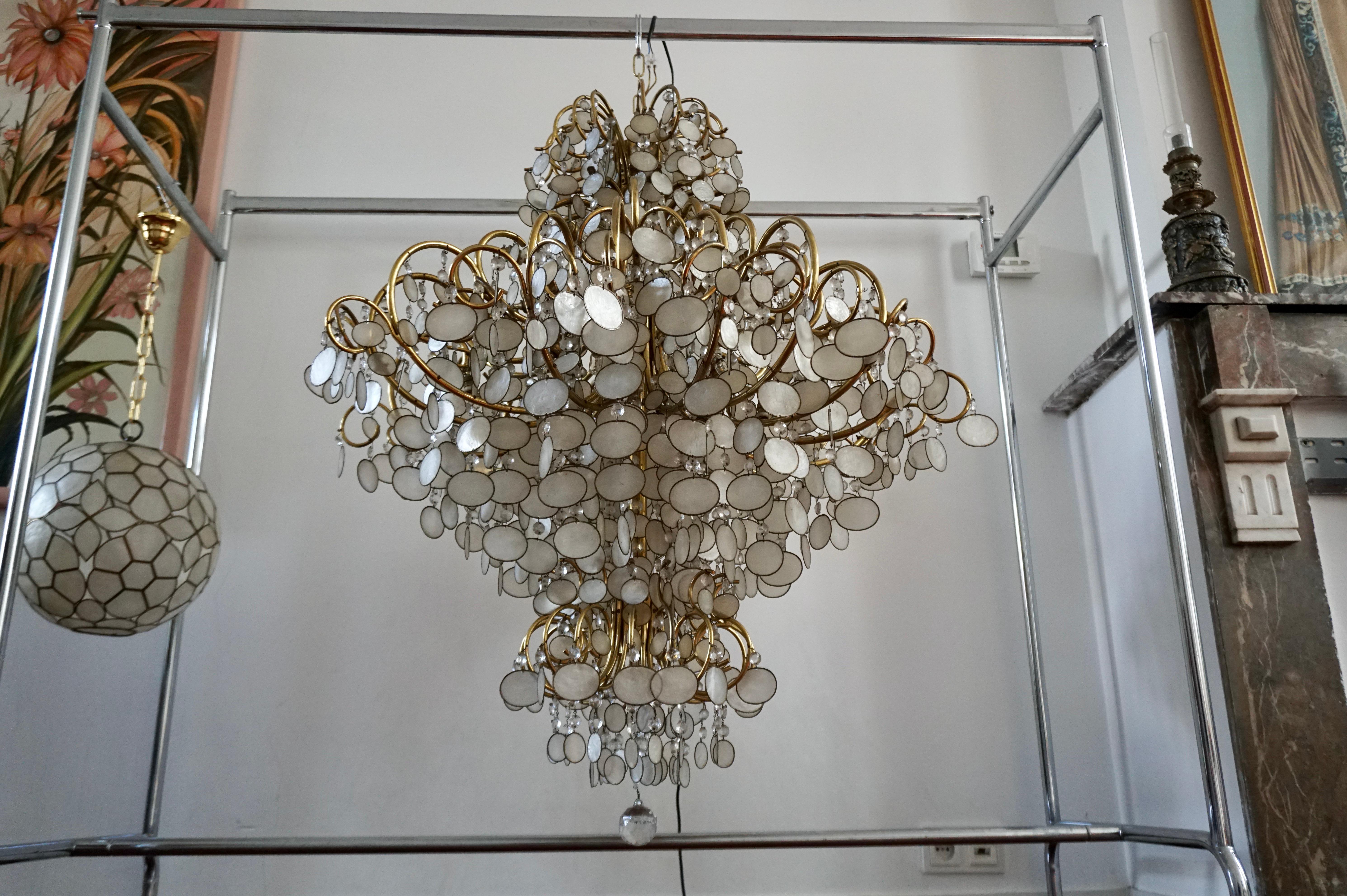 Large chandelier, Europe, 1950s, 1970s.

Large circular 90 cm/36 inch chandelier with many layers of capiz shells.The frame is made of brass and holds numerous round capiz shells in brass rings.Due to the combination of the brass and the big amount
