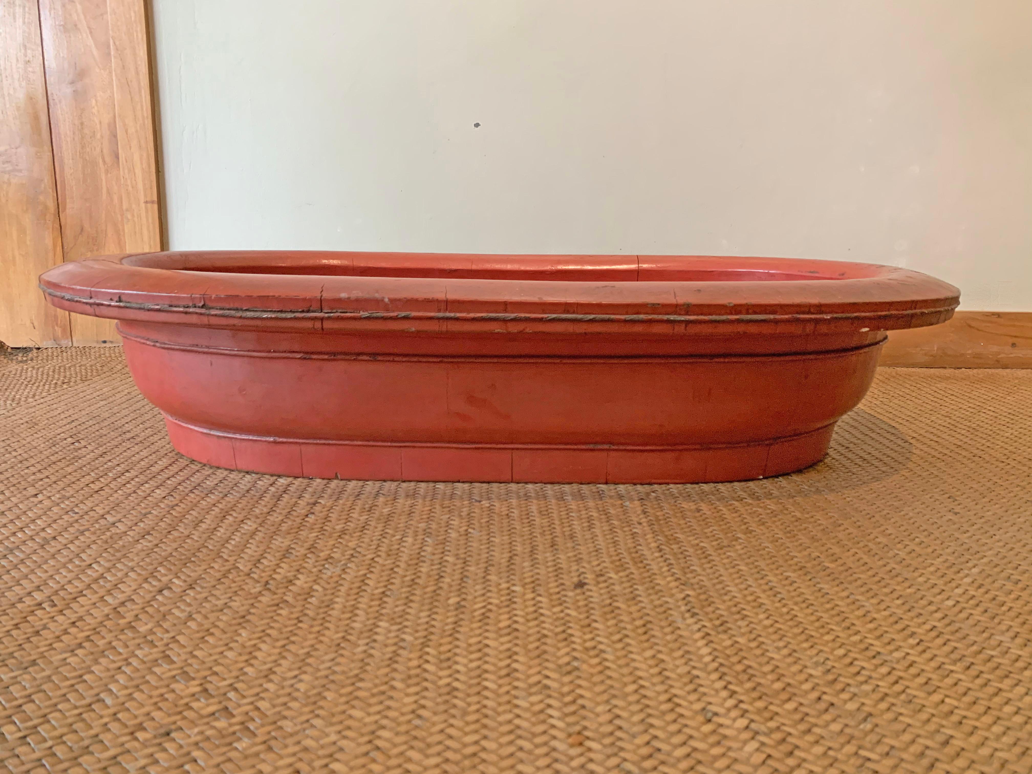 A Chinese Red Lacquer Wood Bowl with a unique oval shape and of exceptional size from the early 20th Century. The age related cracks that have formed on its outer-side add to its appeal. Its large size makes it perfect as a centre display piece on a