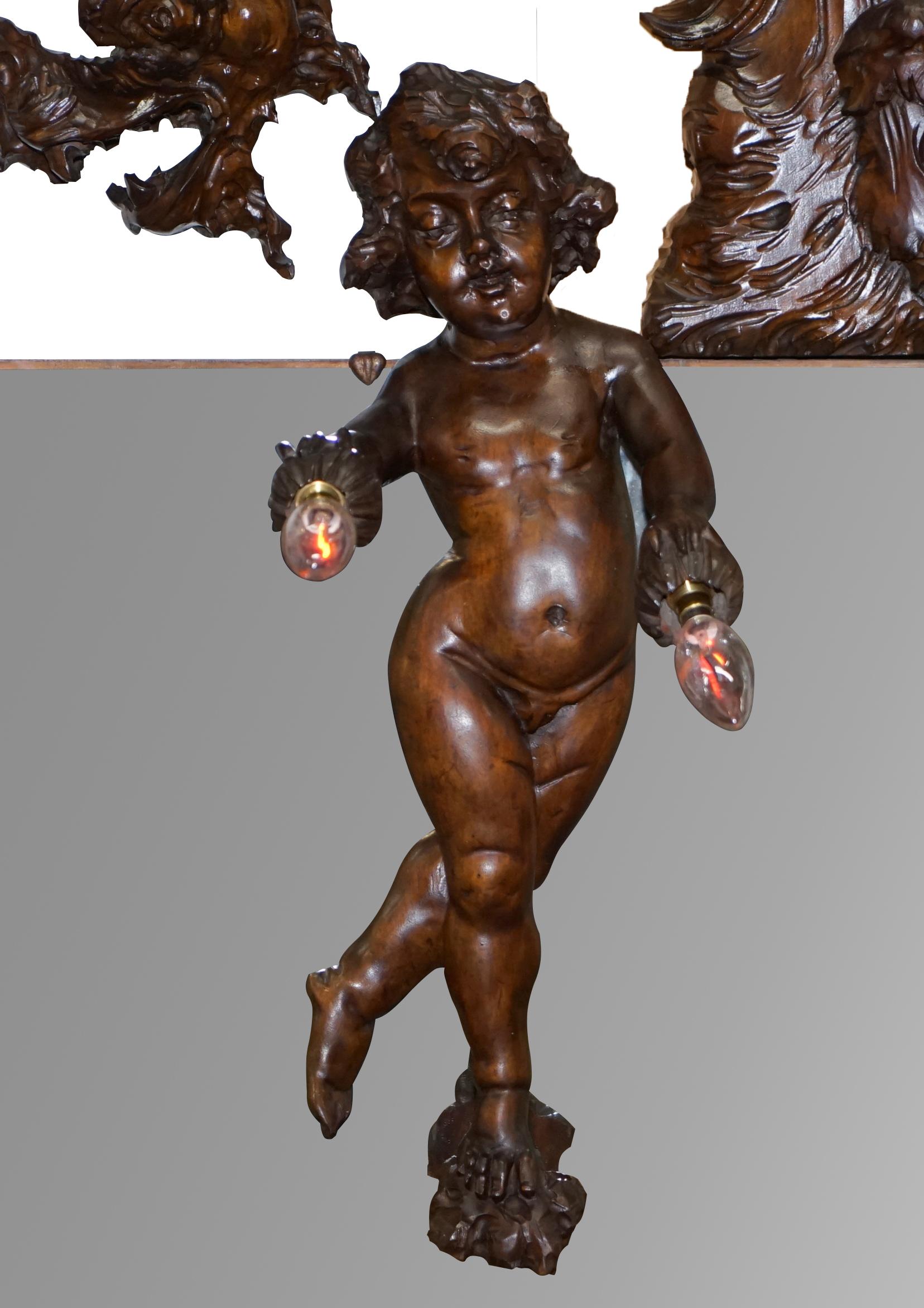 We are delighted to offer for sale this very rare circa 1900 hand carved wall mirror with Putti angel holding two flickering flame bulbs protected by a dragon

A very rare piece, I have never seen another like it, most likely Italian, the Putti is
