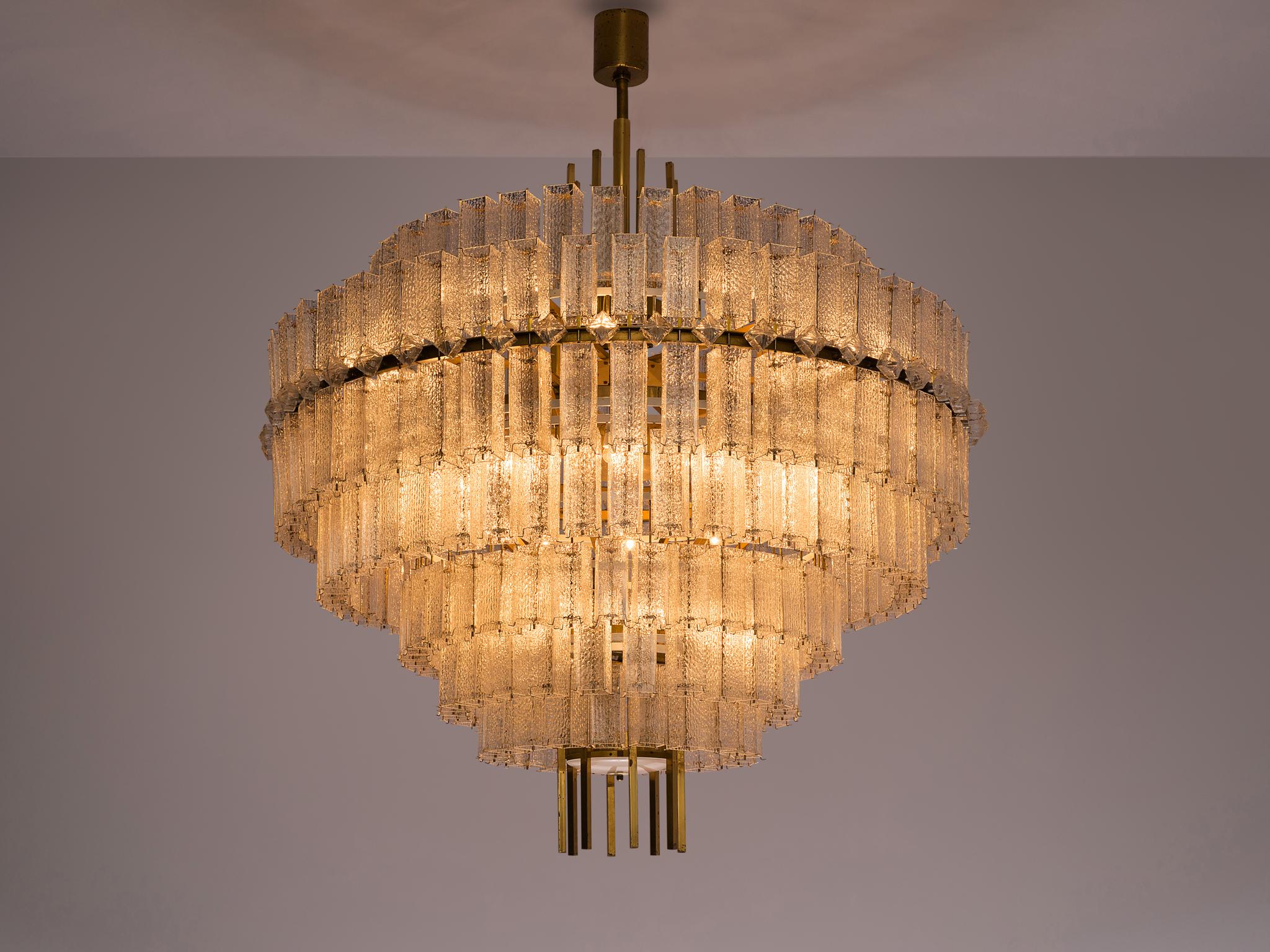 Large chandelier, glass and brass, Europe, 1970s. 

Large circular 200 cm/6.5 ft chandelier with seven layers of glass shades. The frame is made of brass and holds numerous structured glass 'tubes' with a brass centre. Due to the combination of the