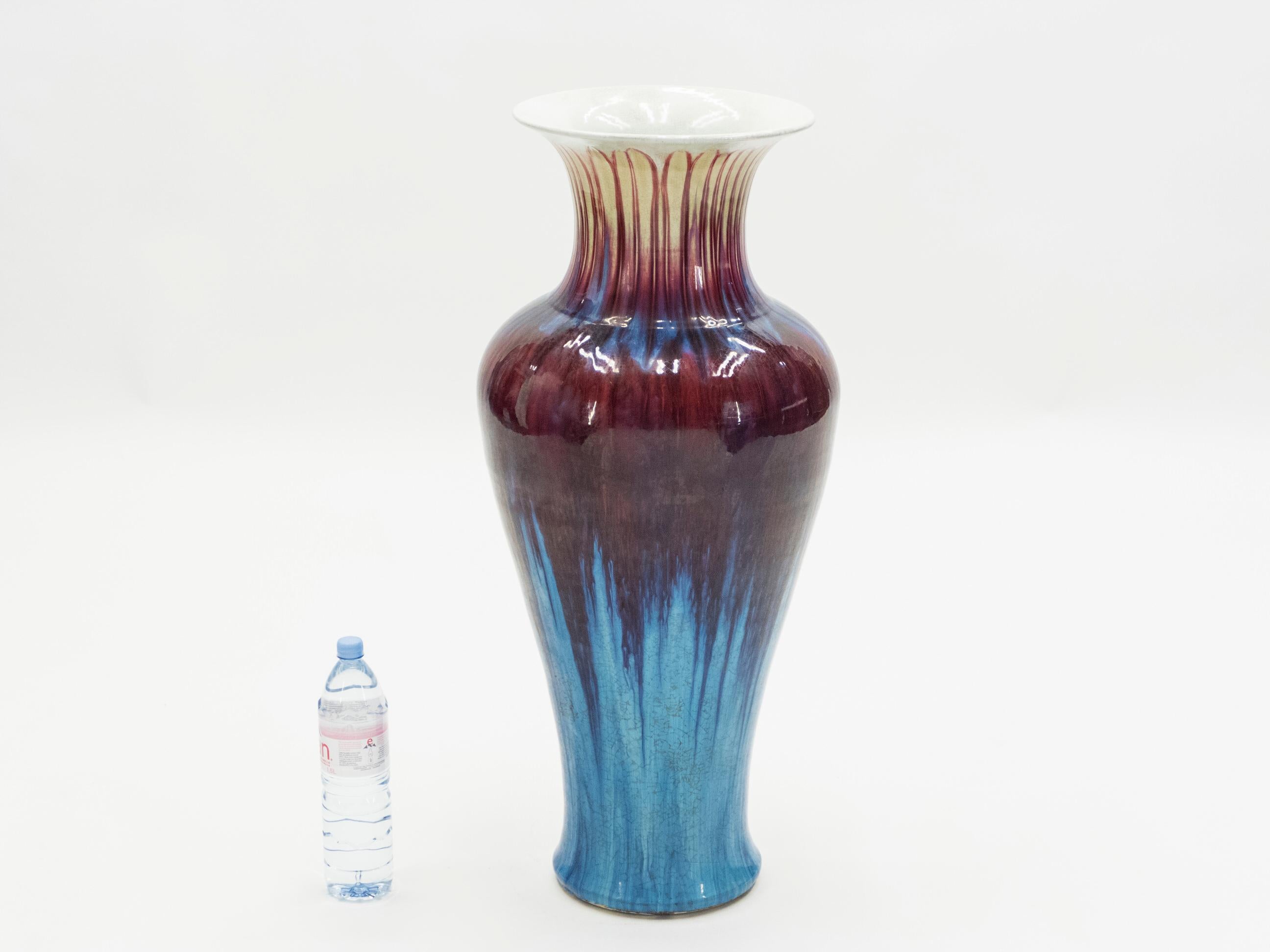 Diese beerenfarbene Keramikvase erinnert stark an die 1960er Jahre. Die tiefen, himbeerroten und bonbonblauen Farben sind um die Vase herum verstreut, wie bei einer Krawattenfärbung. Die roten Blüten erstrecken sich über den breitesten Teil der Vase