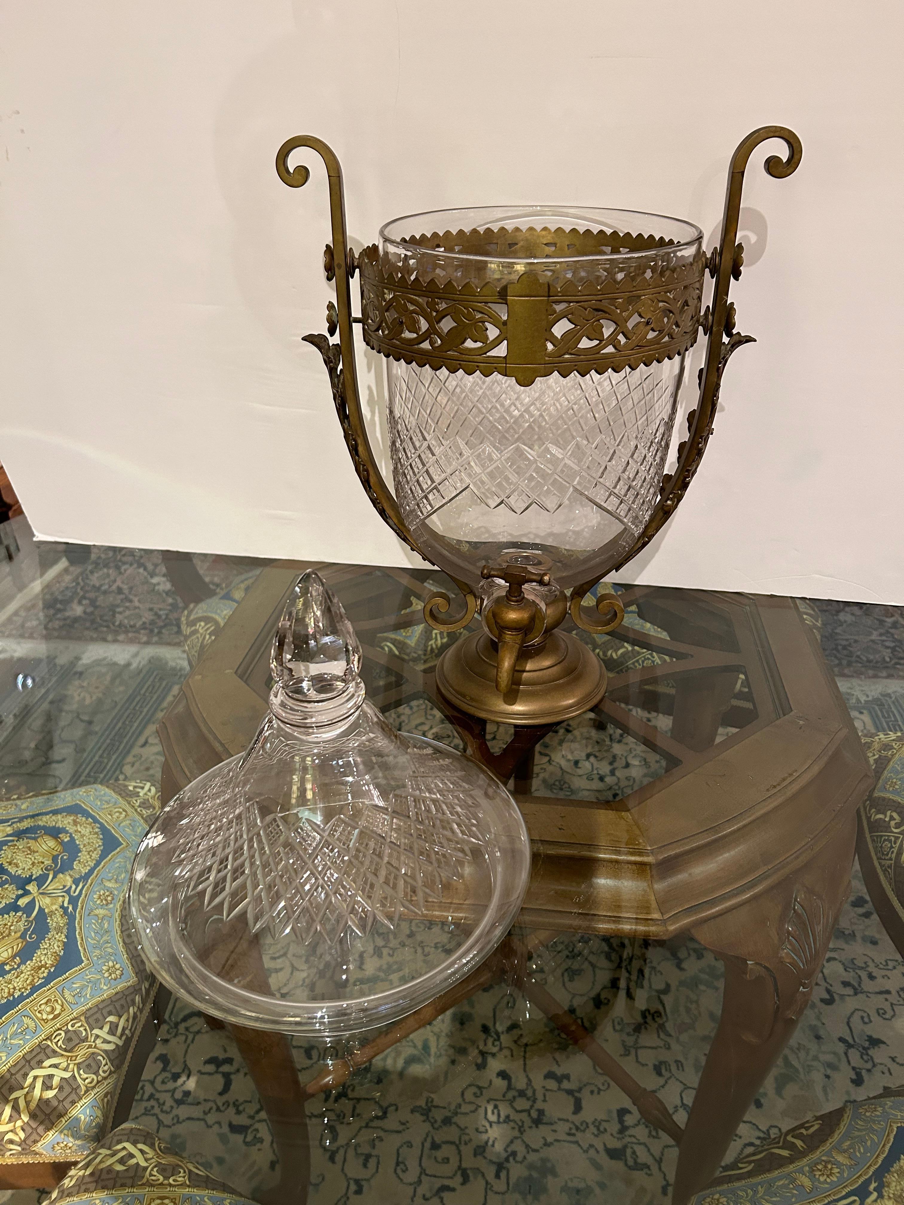 Impressionnant par sa taille, ce grand samovar en cristal taillé est doté d'un joli support décoratif en laiton avec des courbes sur les côtés, d'une base ronde et d'un robinet.  Le samovar est doté d'un couvercle amovible avec un fleuron