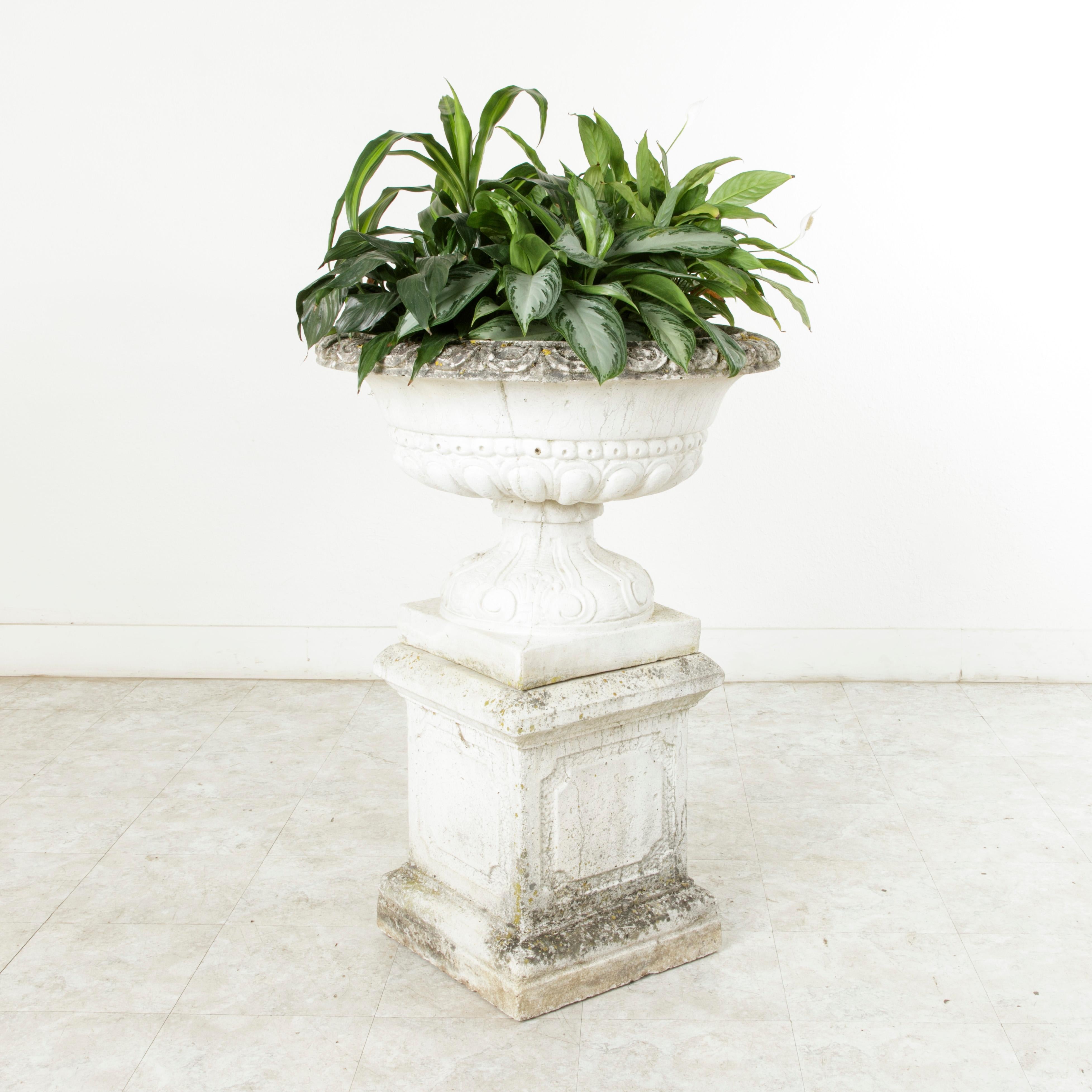 Standing at an impressive 39 inches in height with a 27 inch diameter, this very large mid-twentieth century cast stone planter features a Medicis urn detailed with egg and dart on the rim, and scrolling and shells on the base. The urn rests on a