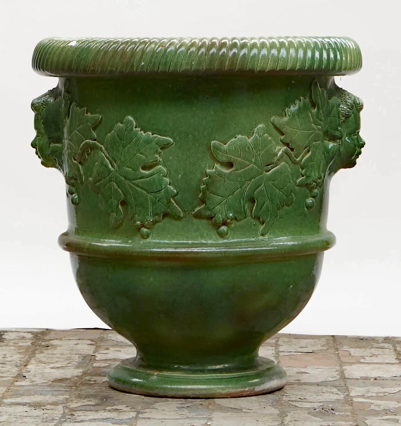 Très grand cache-pot en terre cuite émaillée à décor de visages et de feuilles de vigne circa 1930/1950.
Usure et petites pertes d'émail
