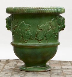 Very large enameled terracotta planter decorated with faces and vine leaves