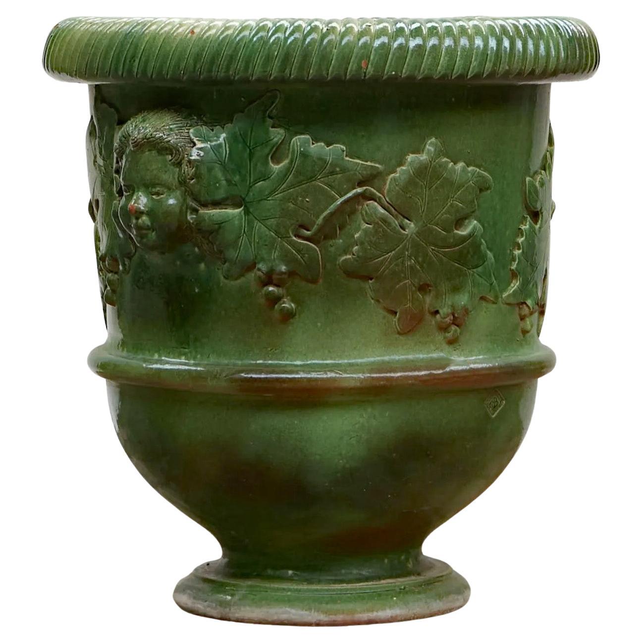 Very large enameled terracotta planter decorated with faces and vine leaves