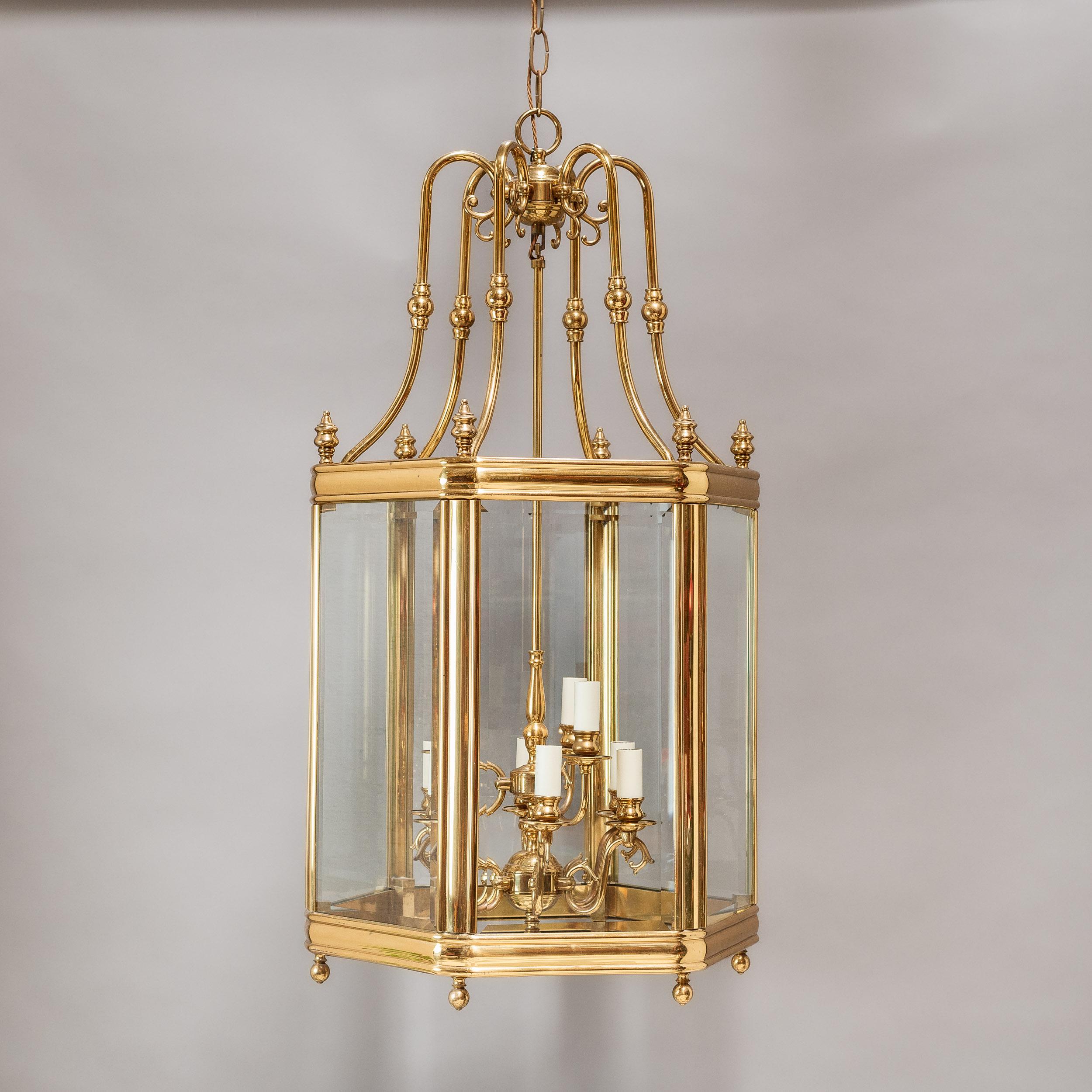 A large eighteenth century style brass hall lantern in the Georgian manner, twentieth century, with knopped and shaped brackets supporting the bevel glass glazed hexagonal body, with eight light suspended fitment within.

Dimensions:	109cm (43