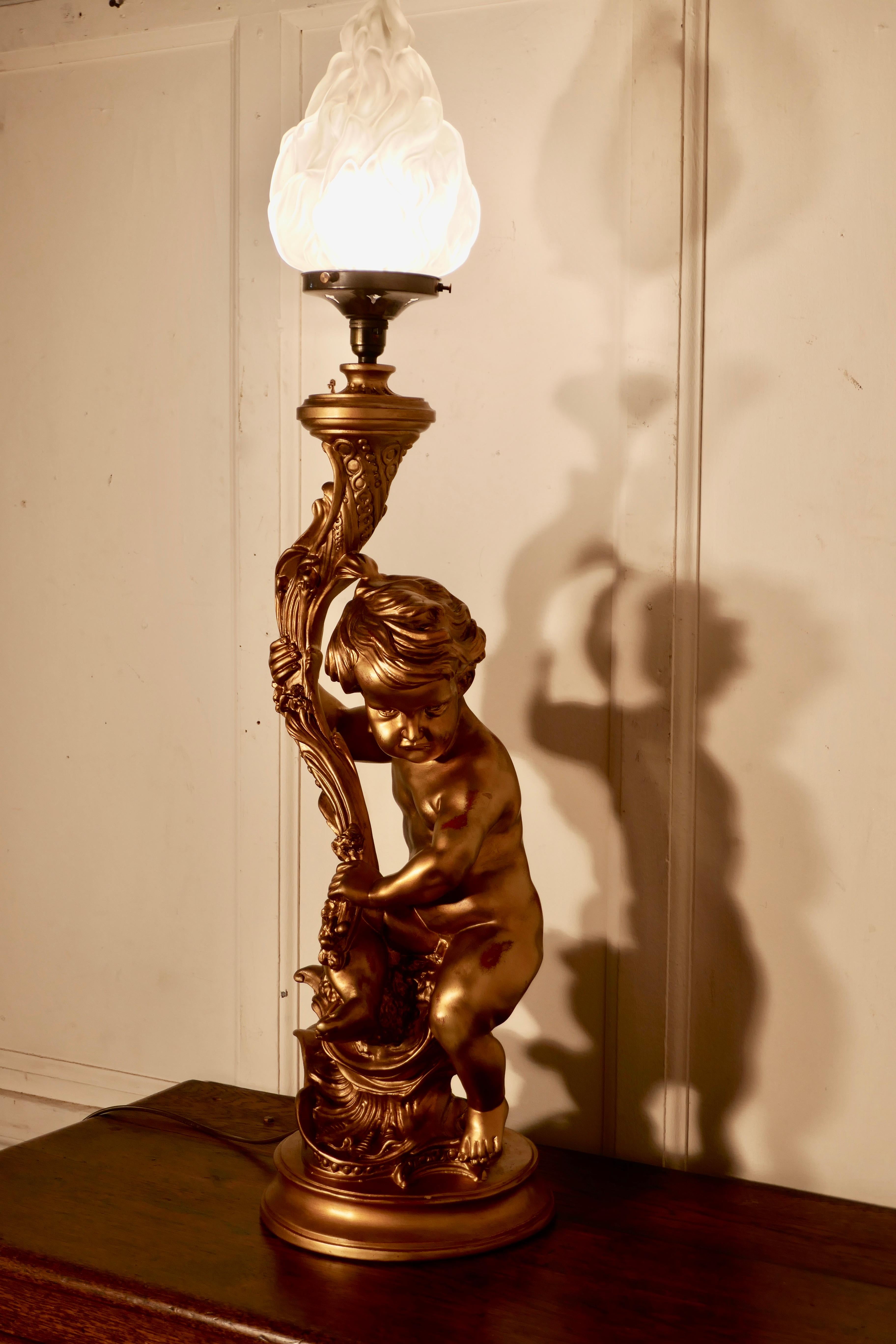 Very large gilt table lamp in the form of a cherub or putti

This charming figure is in gold and is set on a circular plinth, the cherub is holding a glass Art Deco flame lamp shade
The lamp is in good condition, there is some wear to the gilt