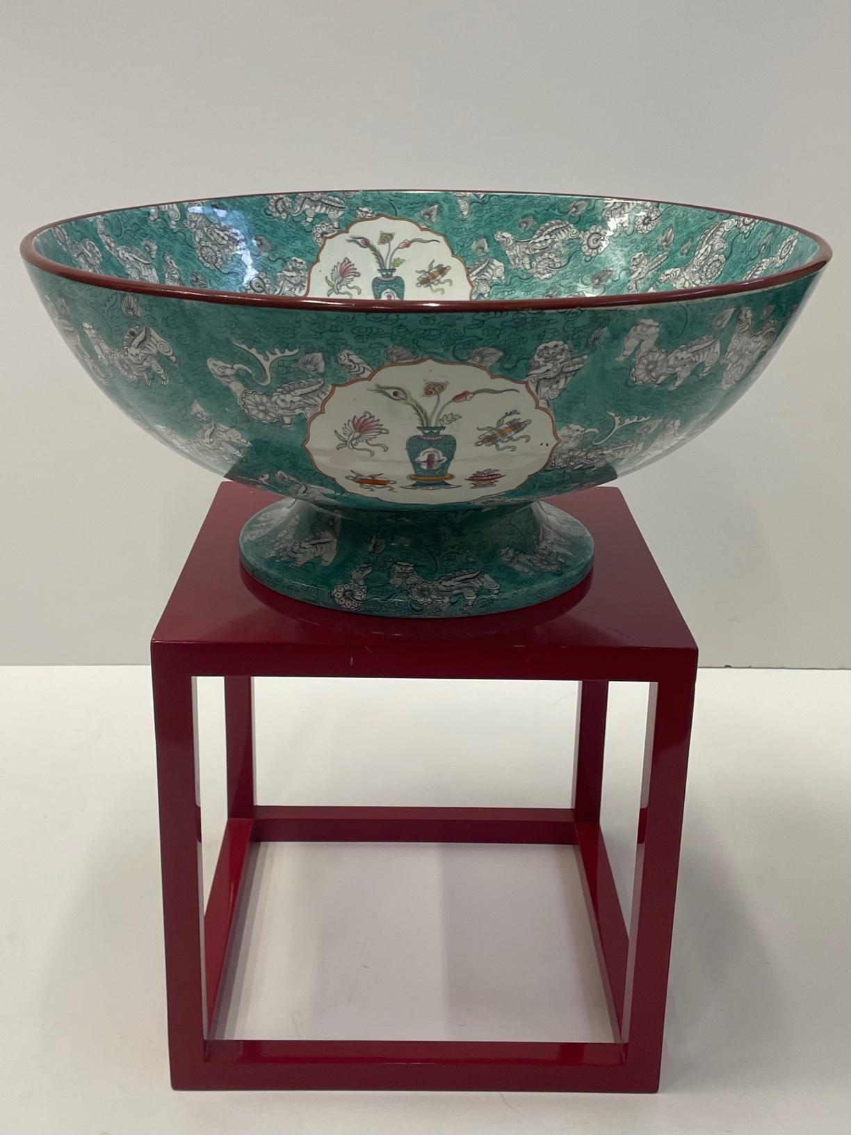 Magnificent large antique English porcelain bowl having sumptuous Asian inspired decoration with foo dogs, vases with flowers, round white medallions and a striking celadon green background. Marked on the bottom.