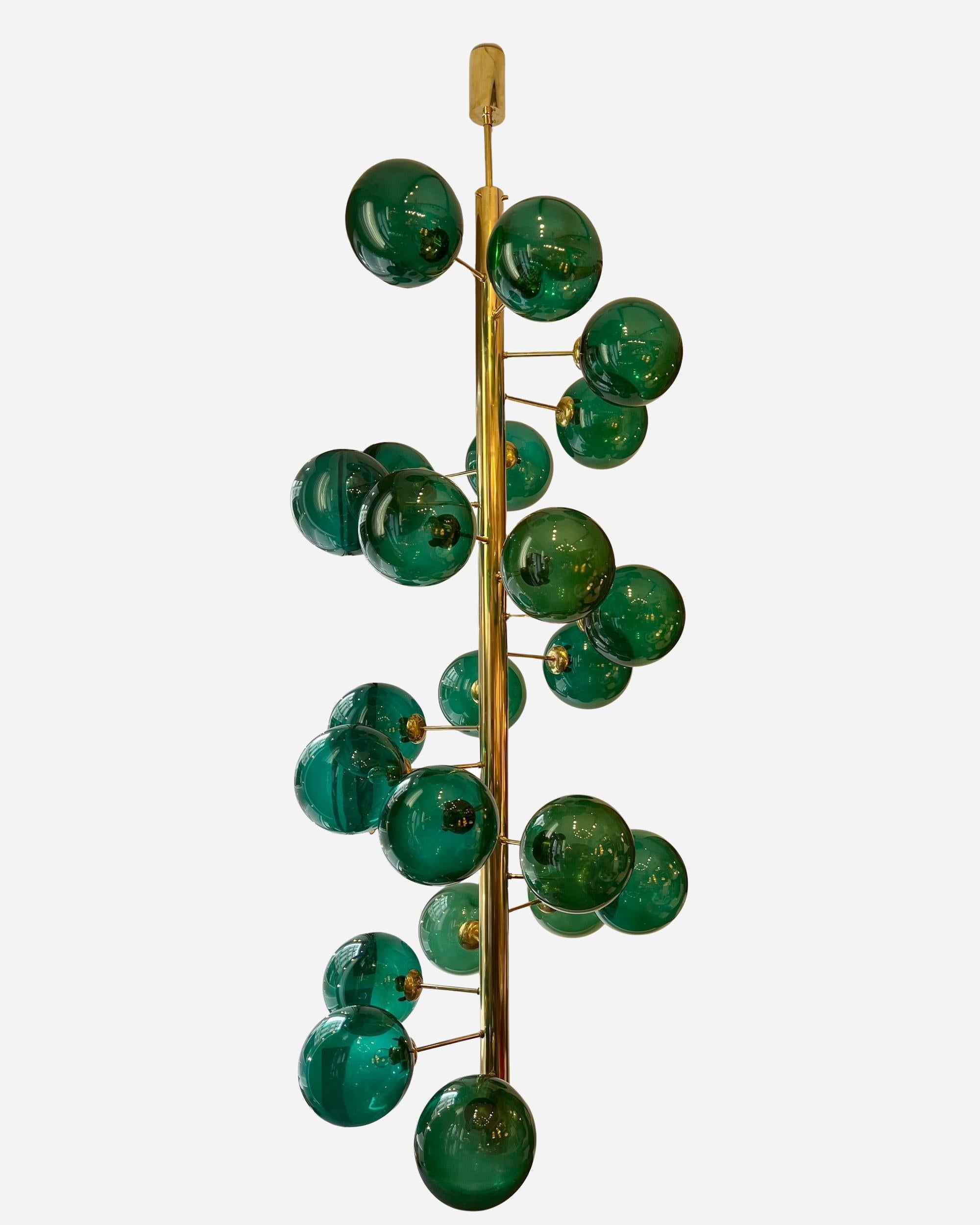 Araña muy grande formada por un eje redondo de latón pulido al que se sujetan veintidós globos transparentes de cristal verde de Vistosi de los años 80.
Artesanía moderna.