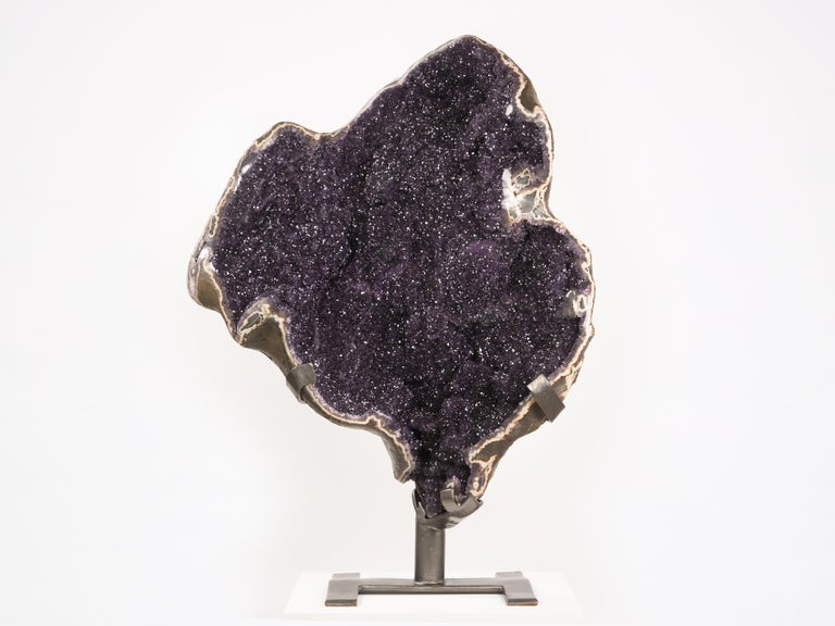 A very large split geode, the interior graced with the finest quality deep purple Uruguayan amethyst.  The amethyst-lined stalactite walls of the geode undulate in and out lending the piece a great depth and dynamic quality.  The agatised borders