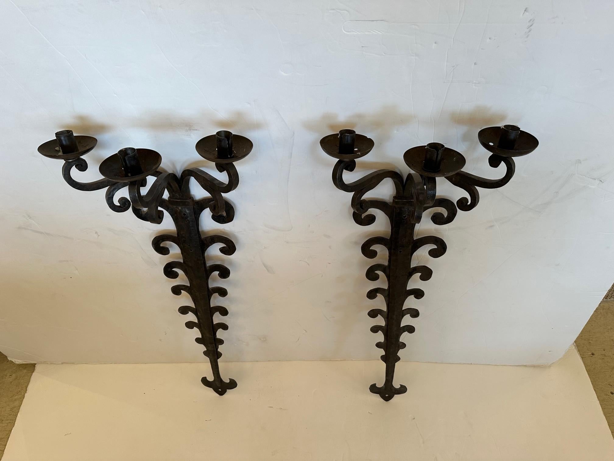 Pair of impressively large hand forged sconces of iron and tole having 3 arms each for candles.  Could be electrified.

