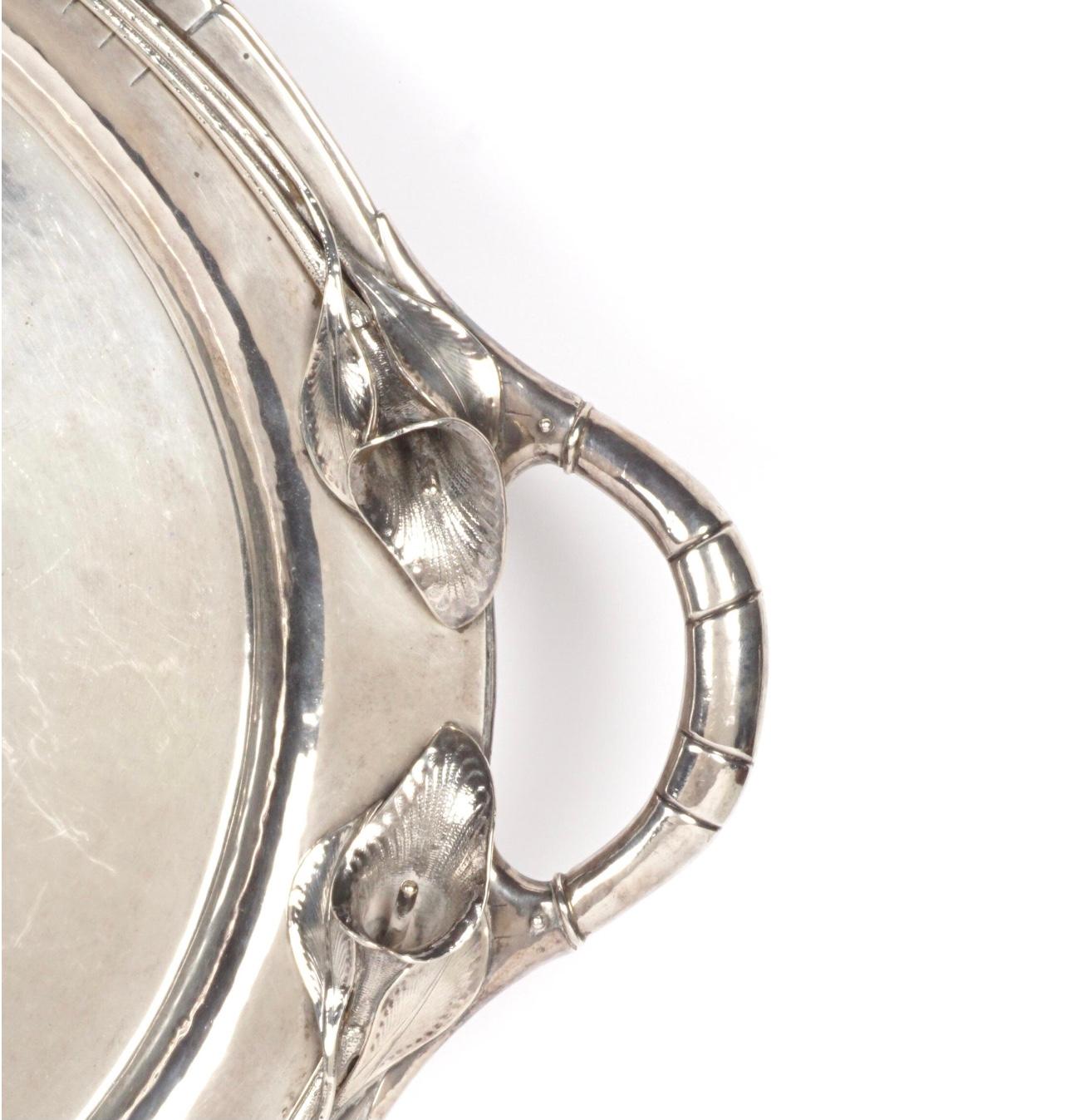 Large double handled serving tray with blossoms around handles. Rim with stylized lilies at handles, marked 
